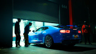 Blue sports car parked outside garage at night
