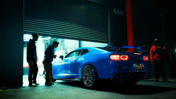 Blue sports car parked outside garage at night