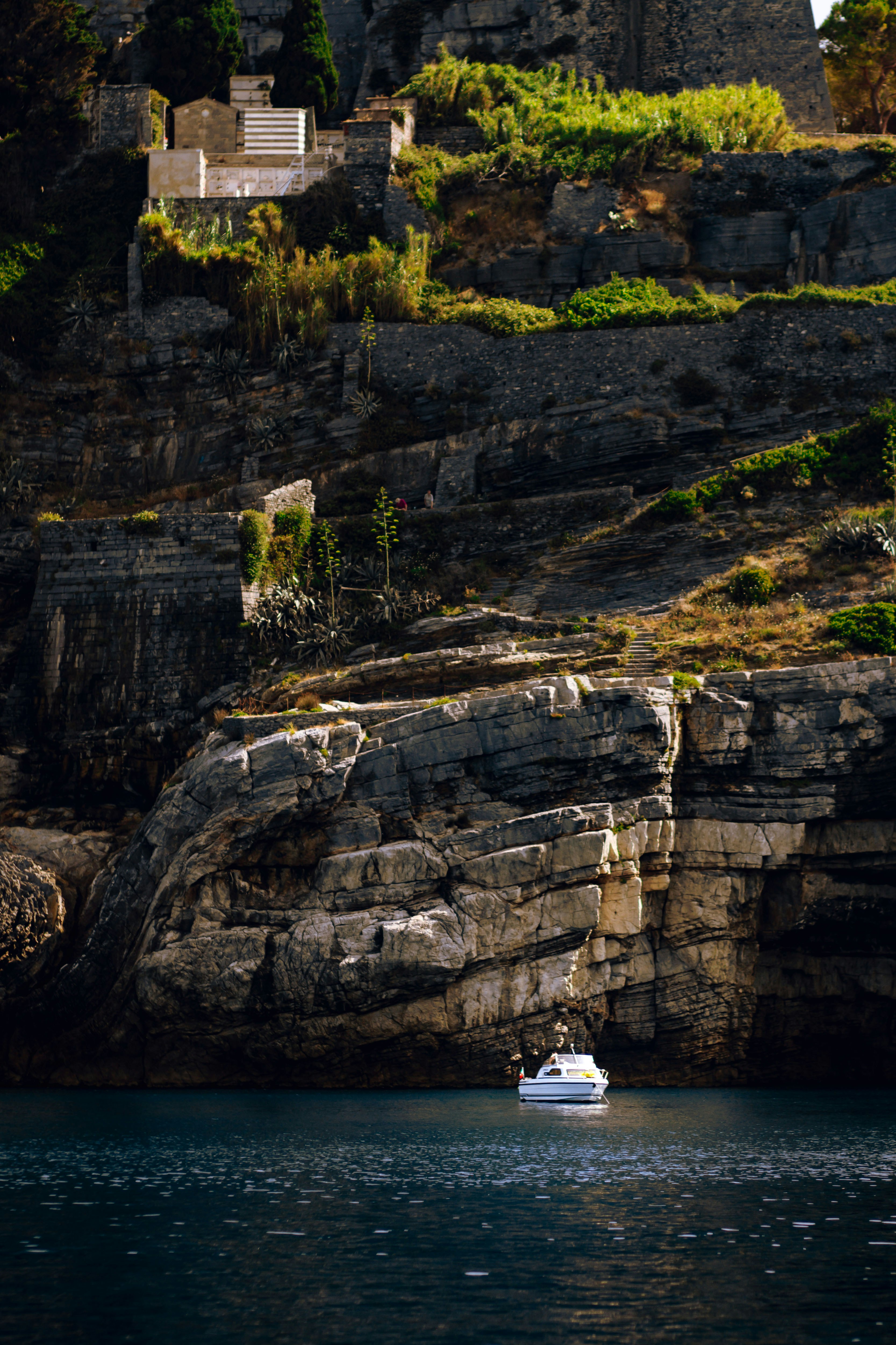 A small boat floats near rocky cliffs.