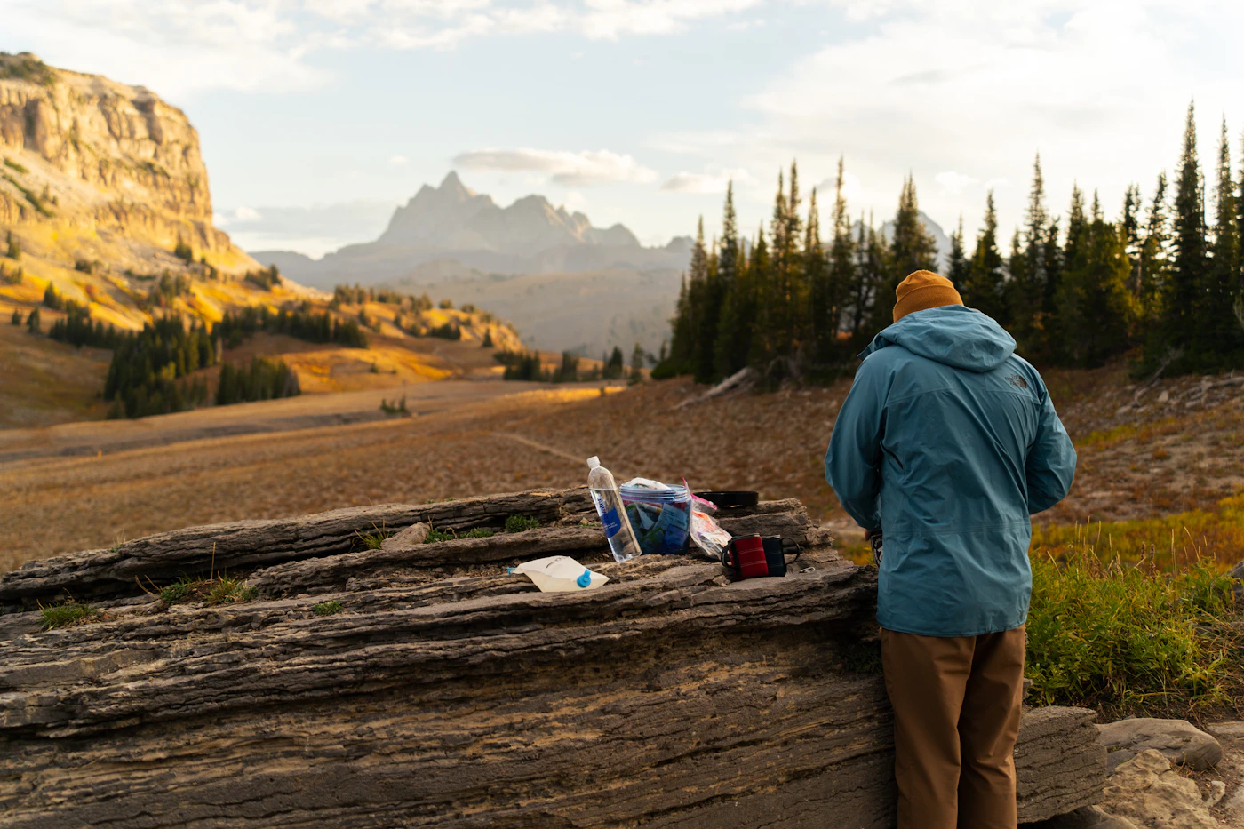 An outdoor traveler preparing gear beside a mountain trail