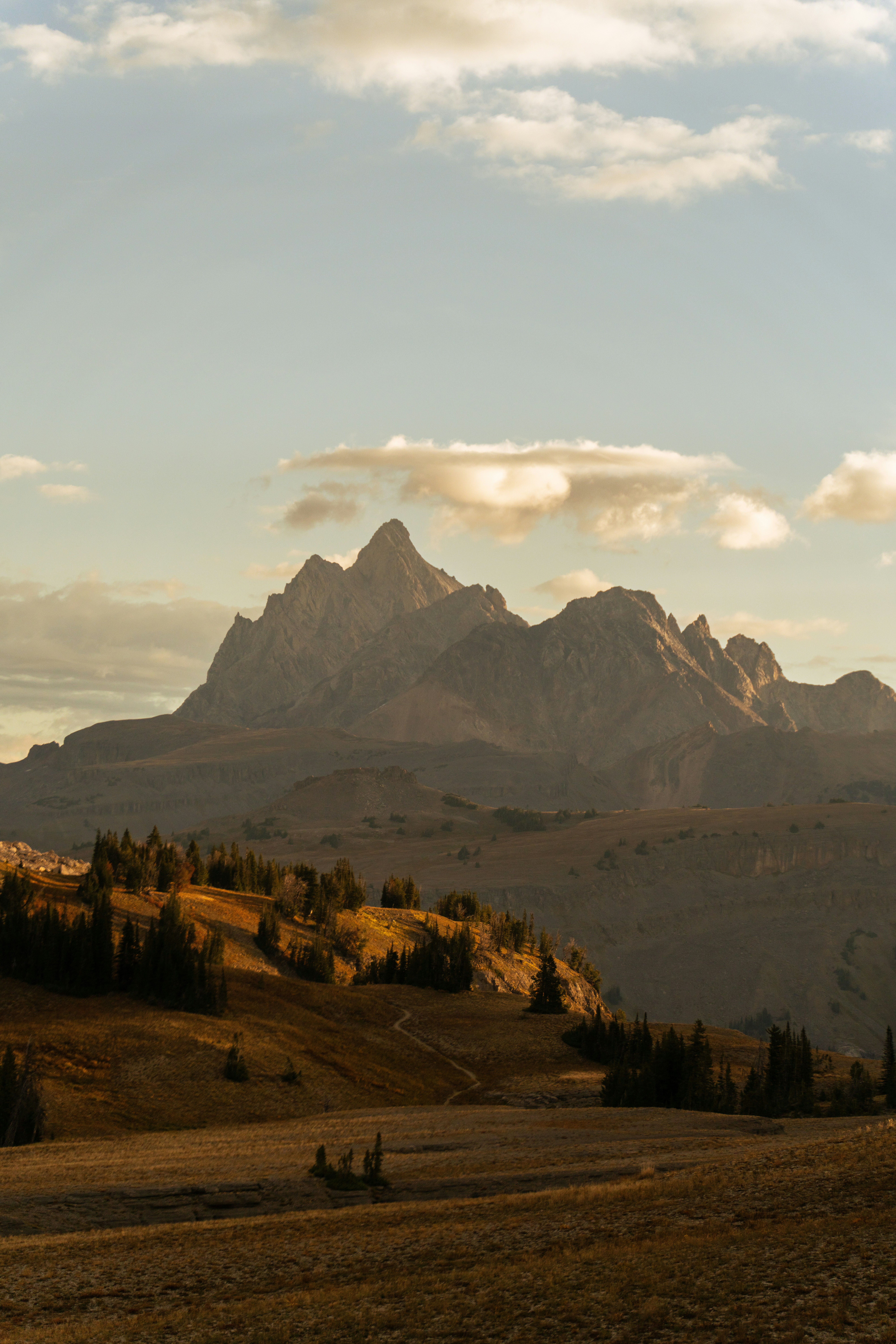 Pics montagneux déchiquetés au coucher du soleil avec des collines dorées