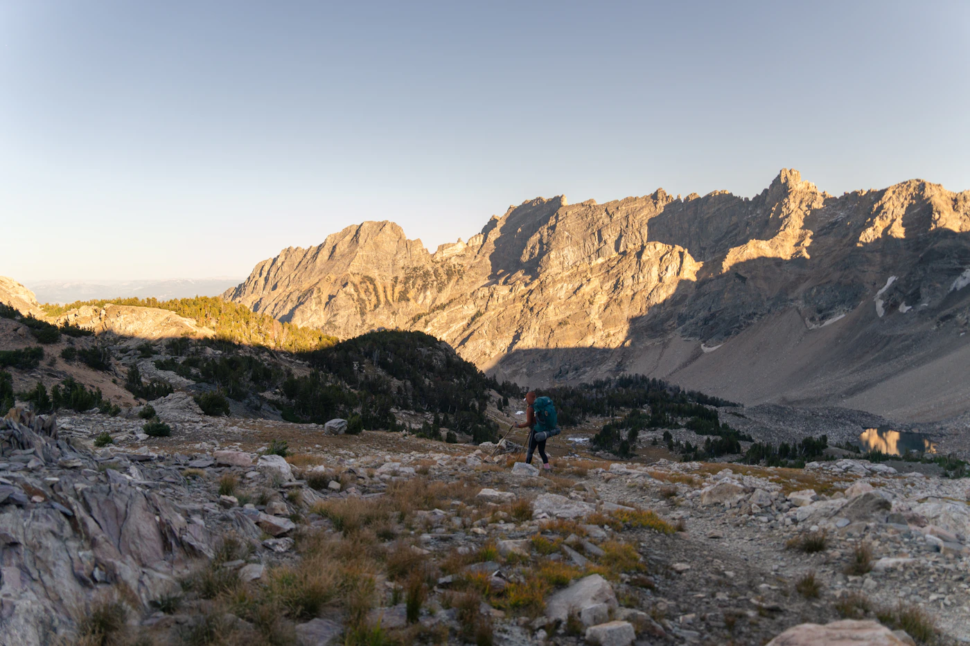 A hiker moving through a rugged alpine mountain landscape