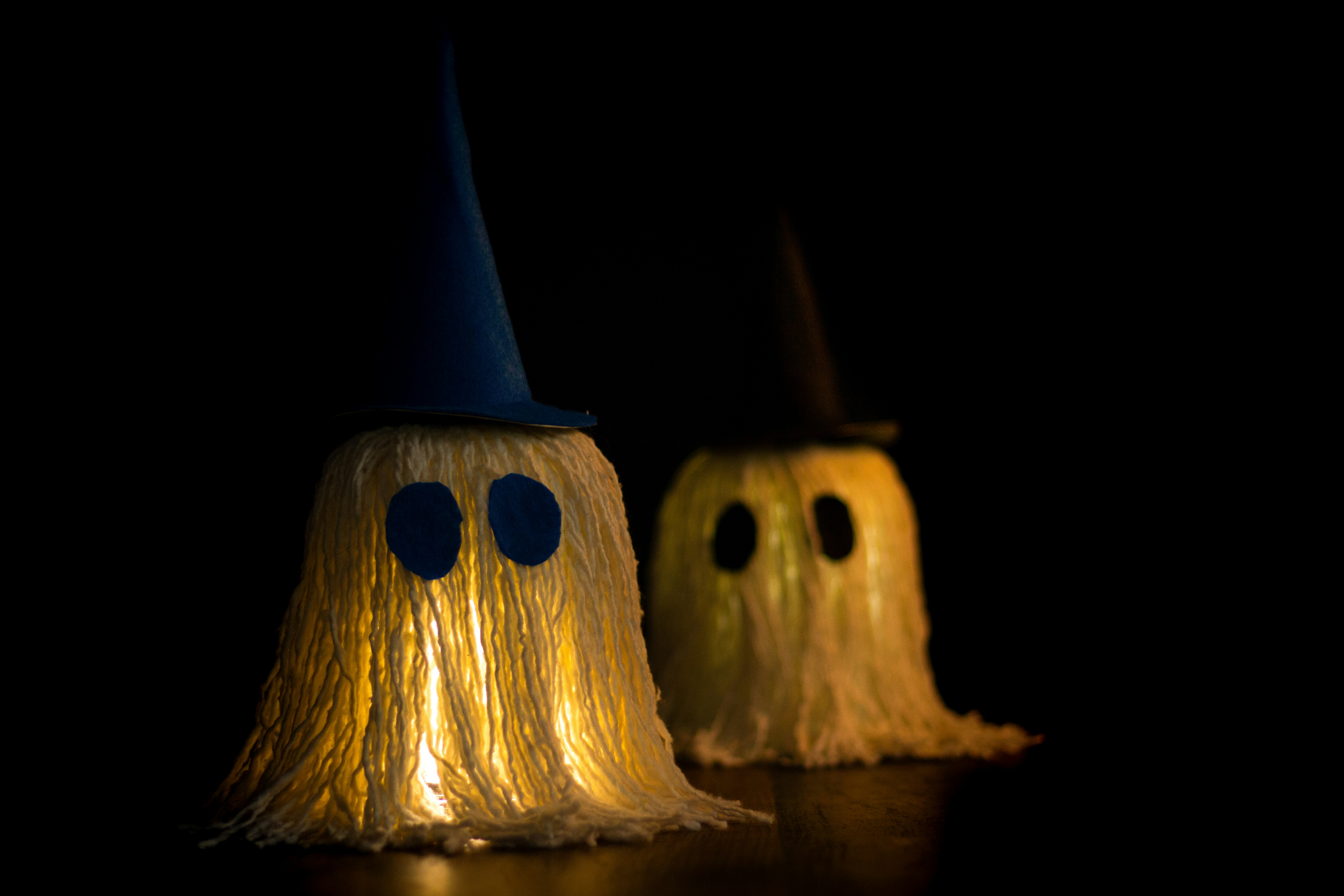 Two glowing ghost crafts wearing wizard hats at night