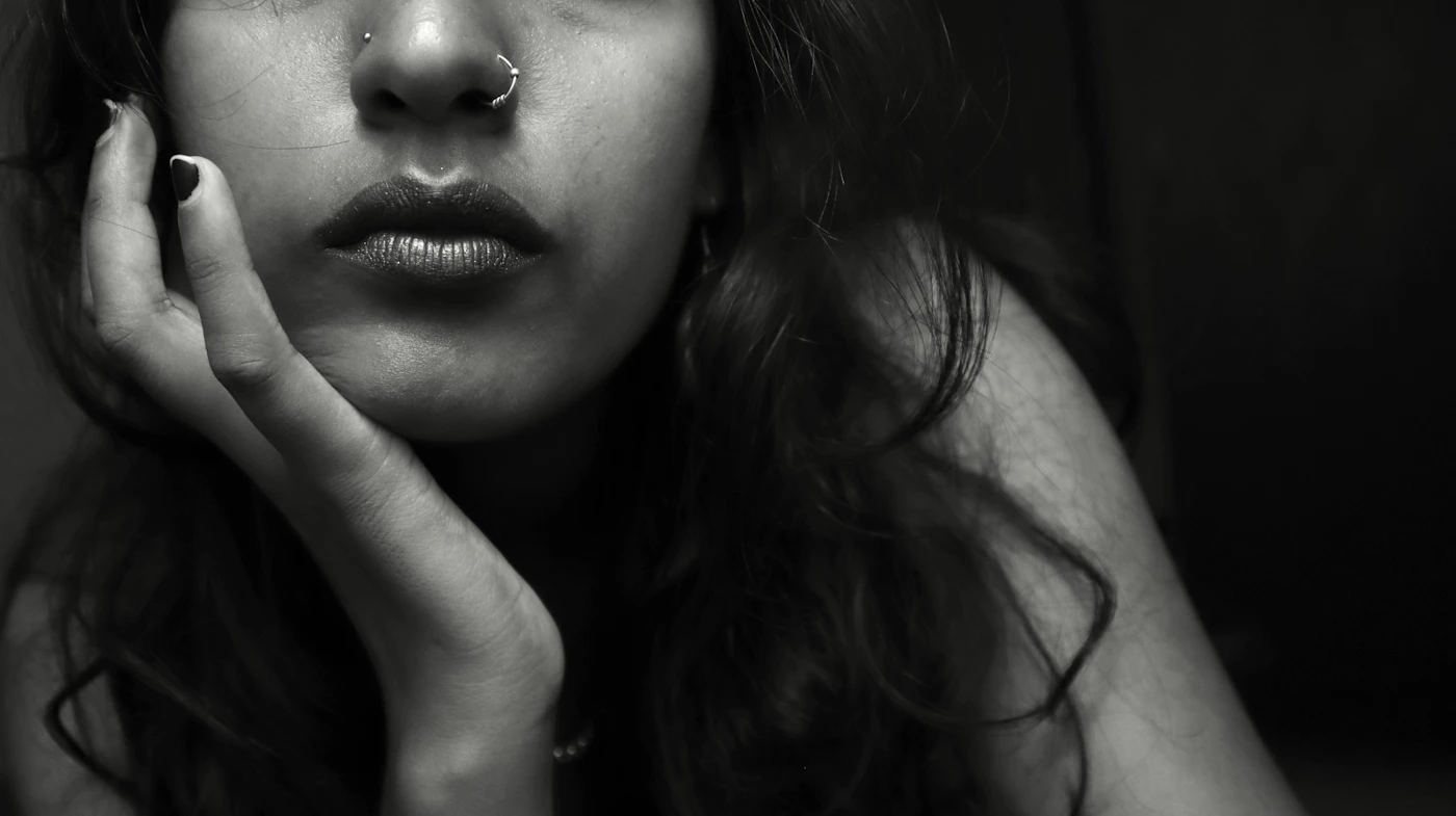 Close-up portrait of a woman with her hand near her chin and jaw during TMJ botulinum toxin treatment review