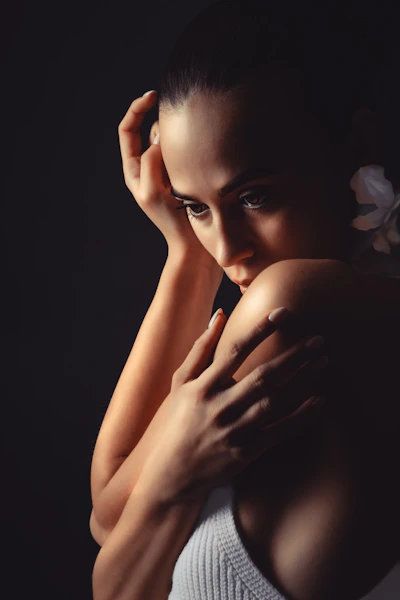 Woman with flower in her hair against dark background