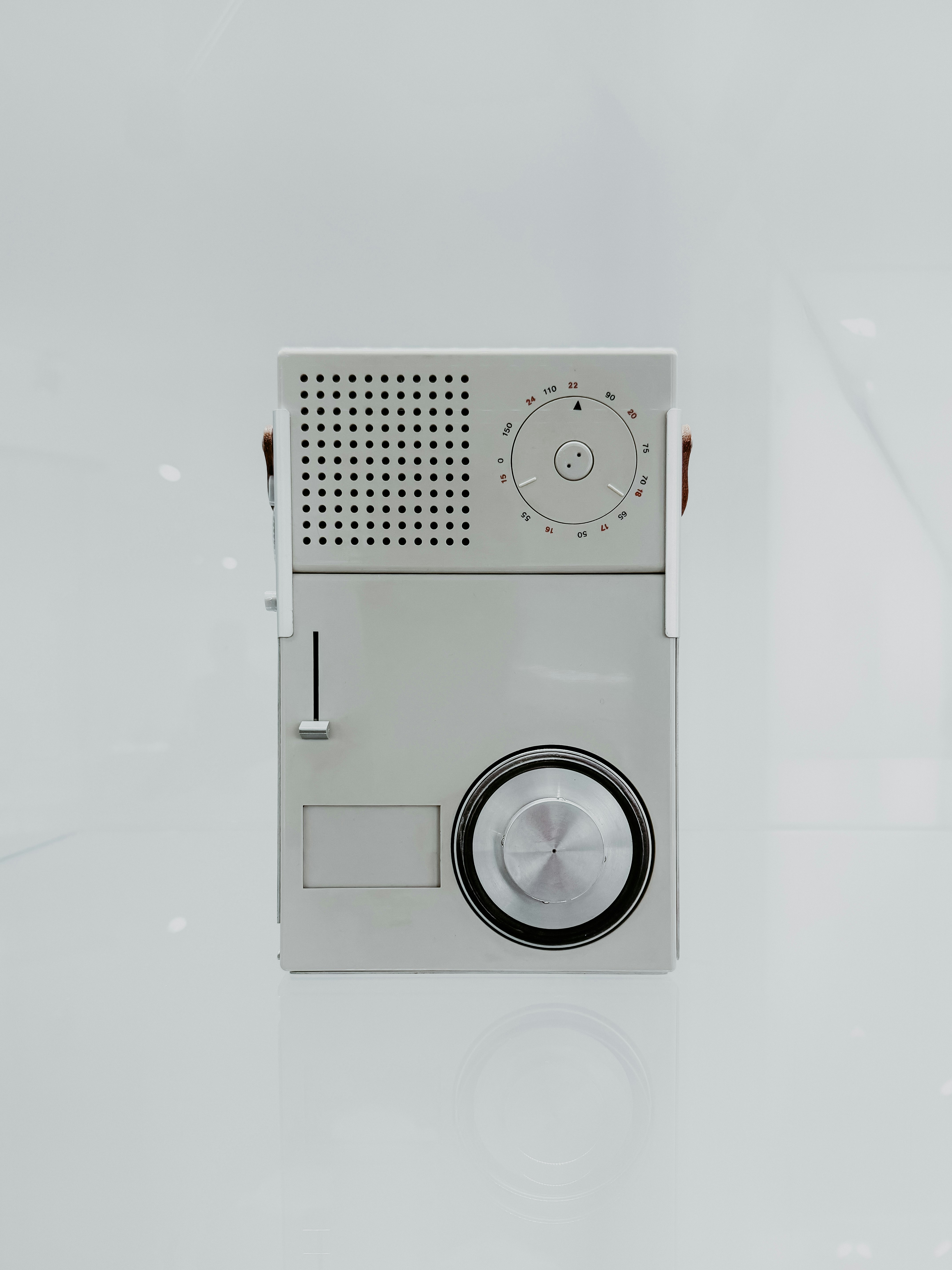 A vintage silver transistor radio sits on a white surface.