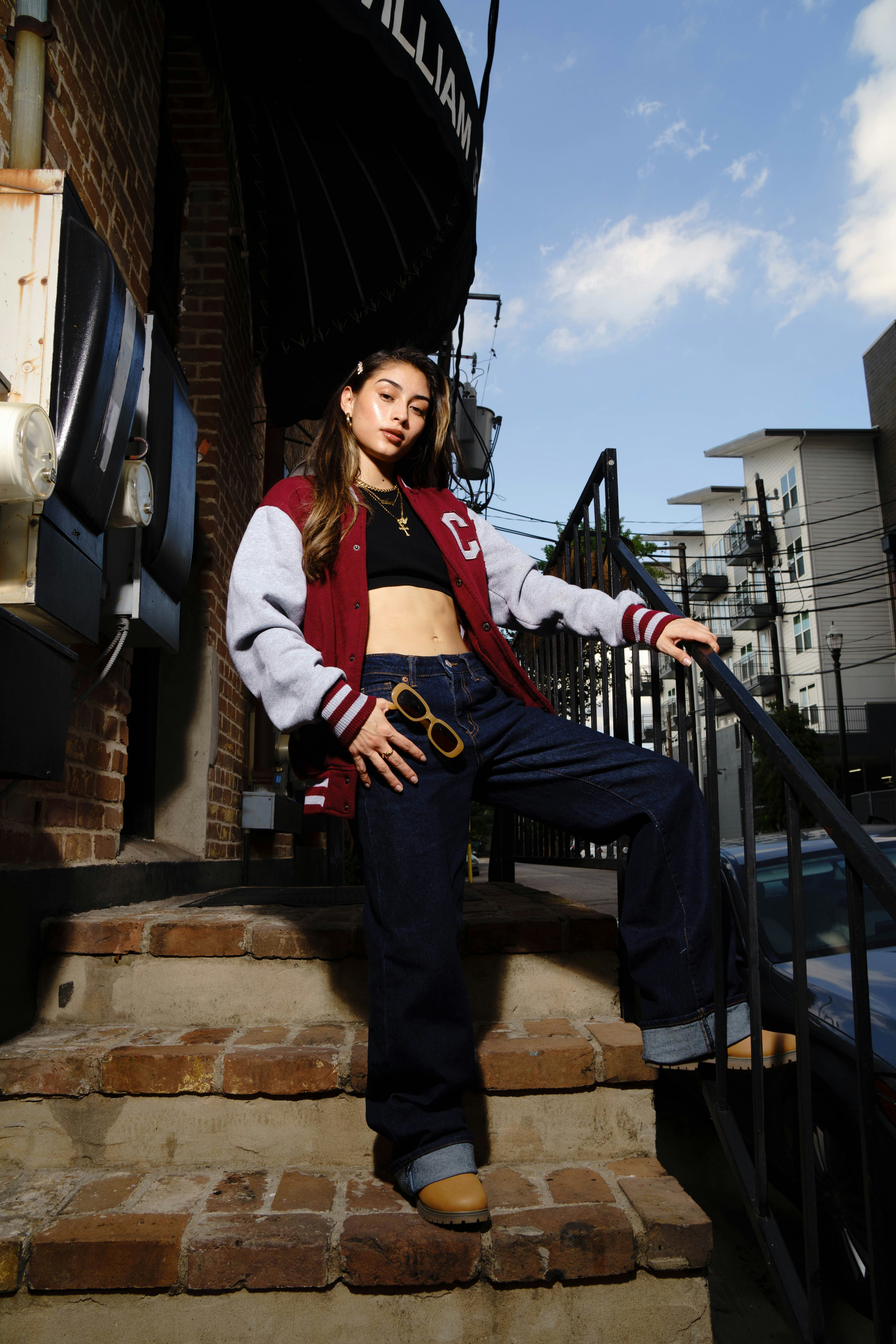 Young woman in a varsity jacket on outdoor stairs