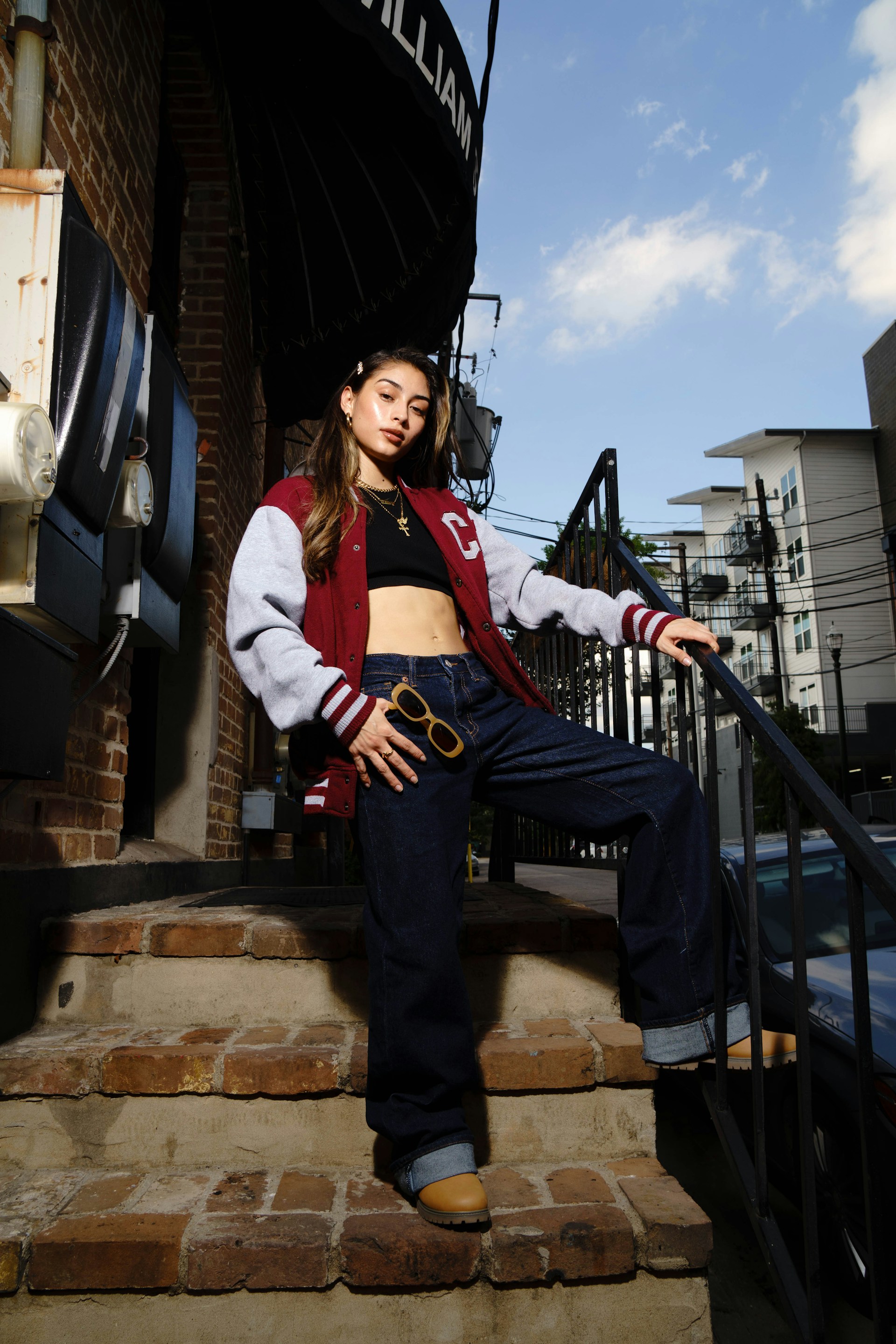 Young woman in a varsity jacket on outdoor stairs