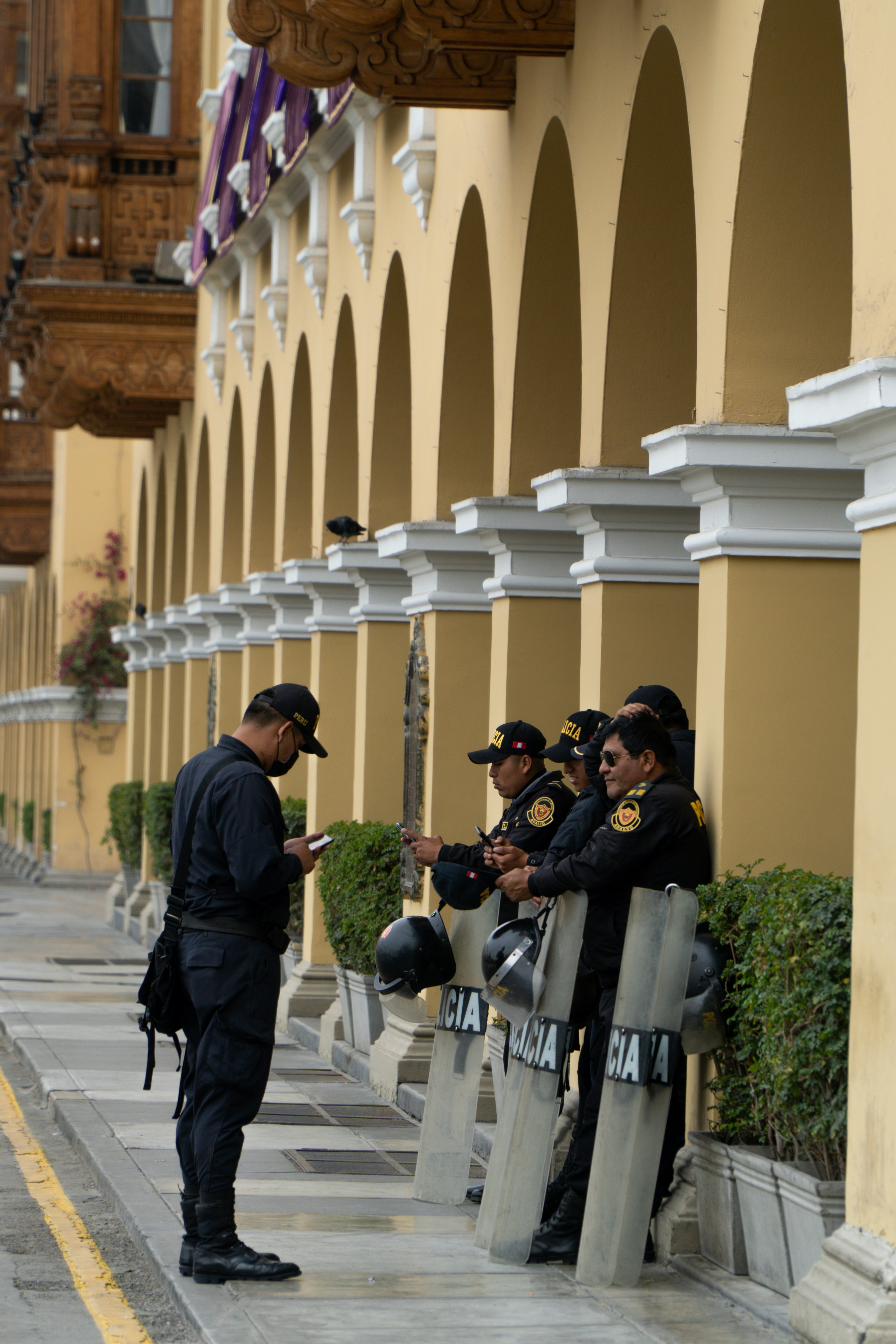 Police officers stand in formation with shields.