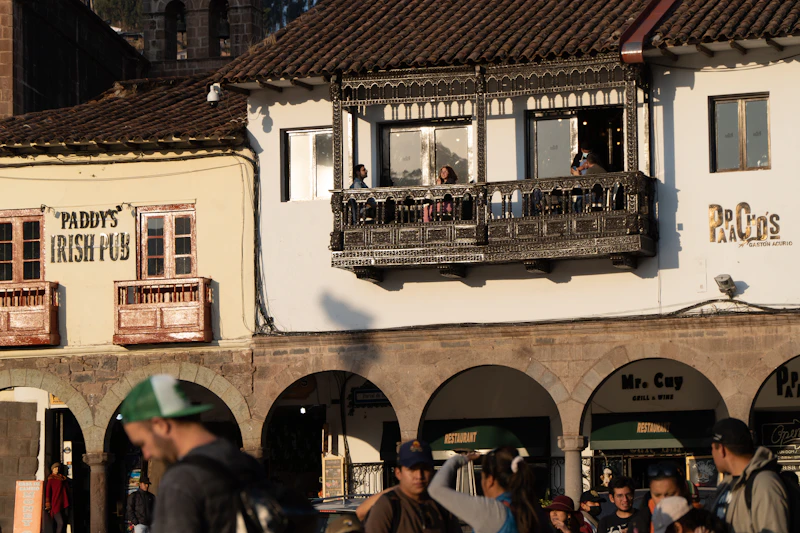 Wooden colonial balconies over a Cusco street with people walking below