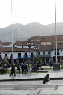 People gather in a town square with mountains behind.