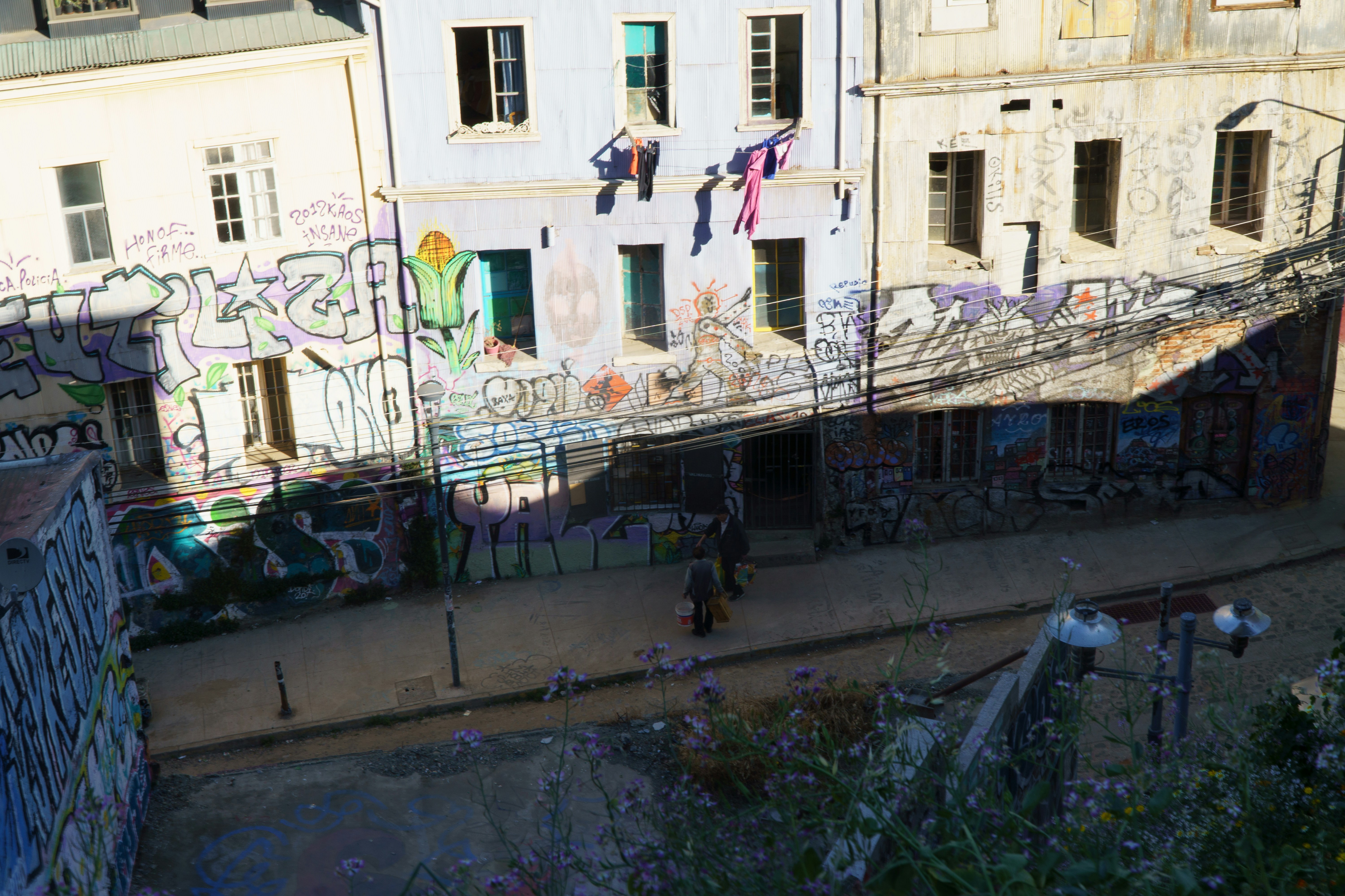 Graffiti covered buildings line a sunny street.