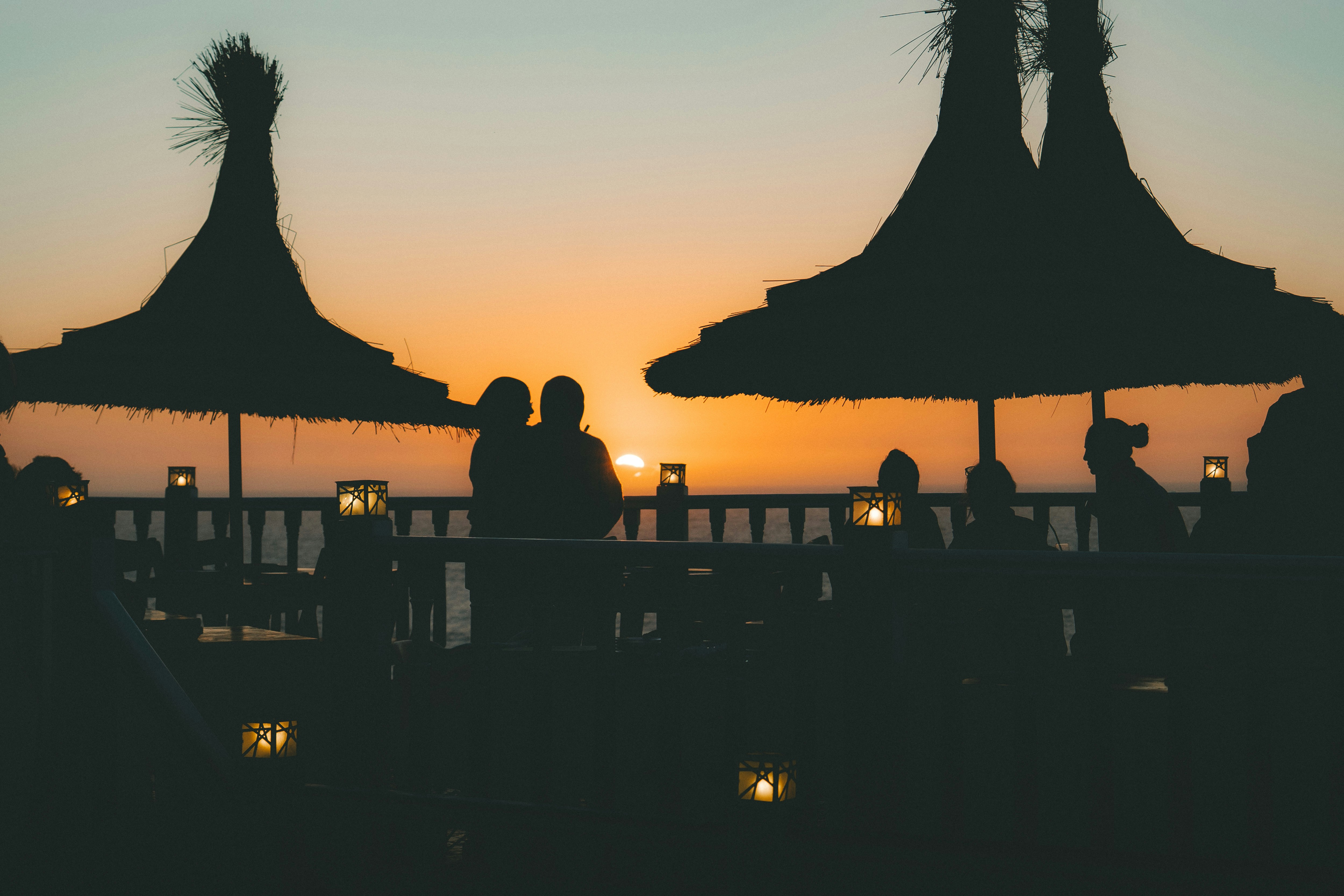 Couple silhouetted against a sunset on a beach