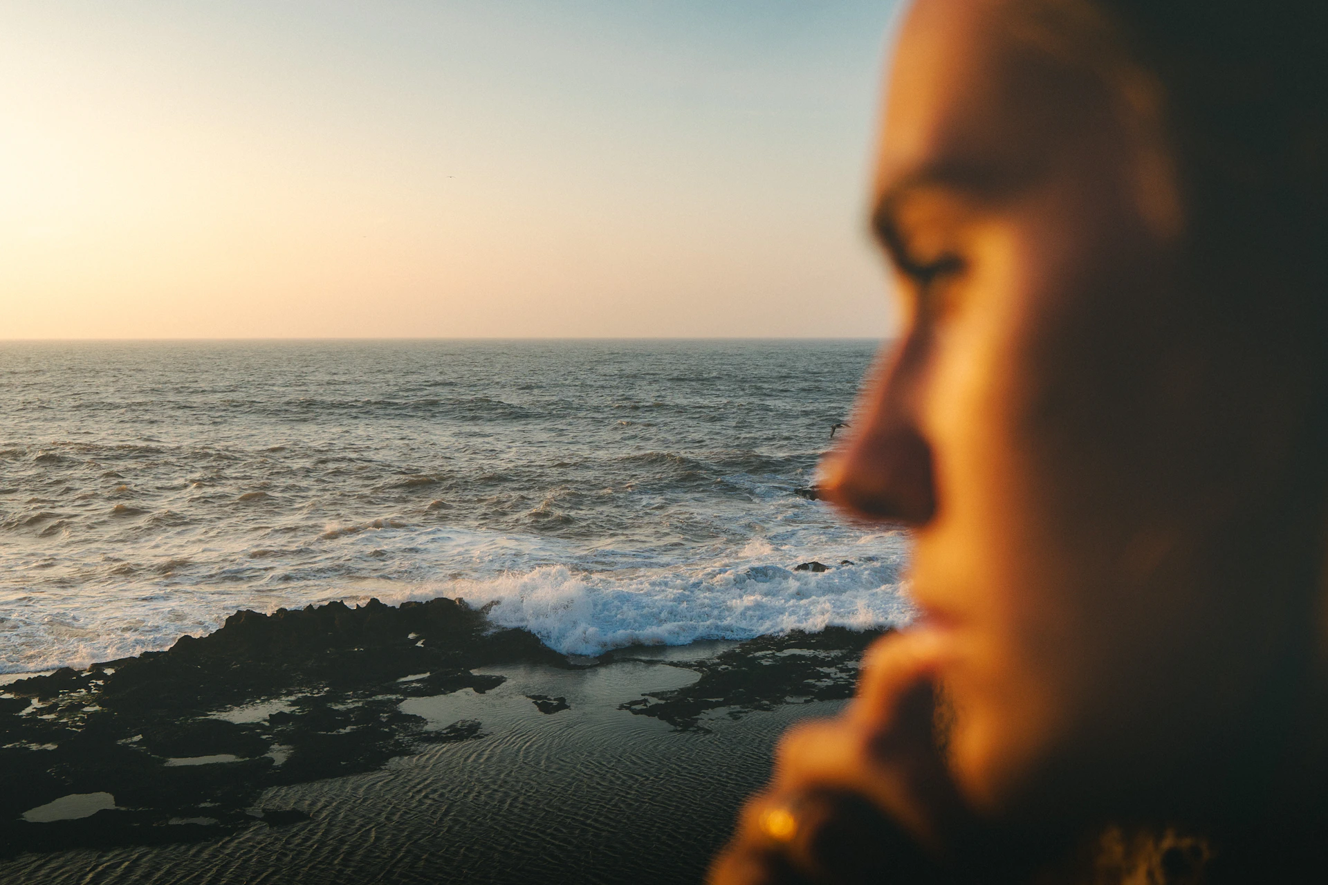 Woman looking at the ocean at sunset