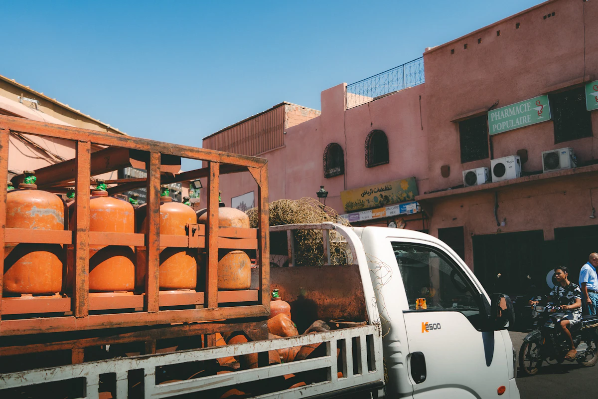 Truck carrying orange propane cylinders through a city street
