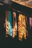 Colorful scarves hanging in sunlight with shadows.