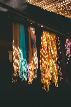 Colorful scarves hanging in sunlight with shadows.