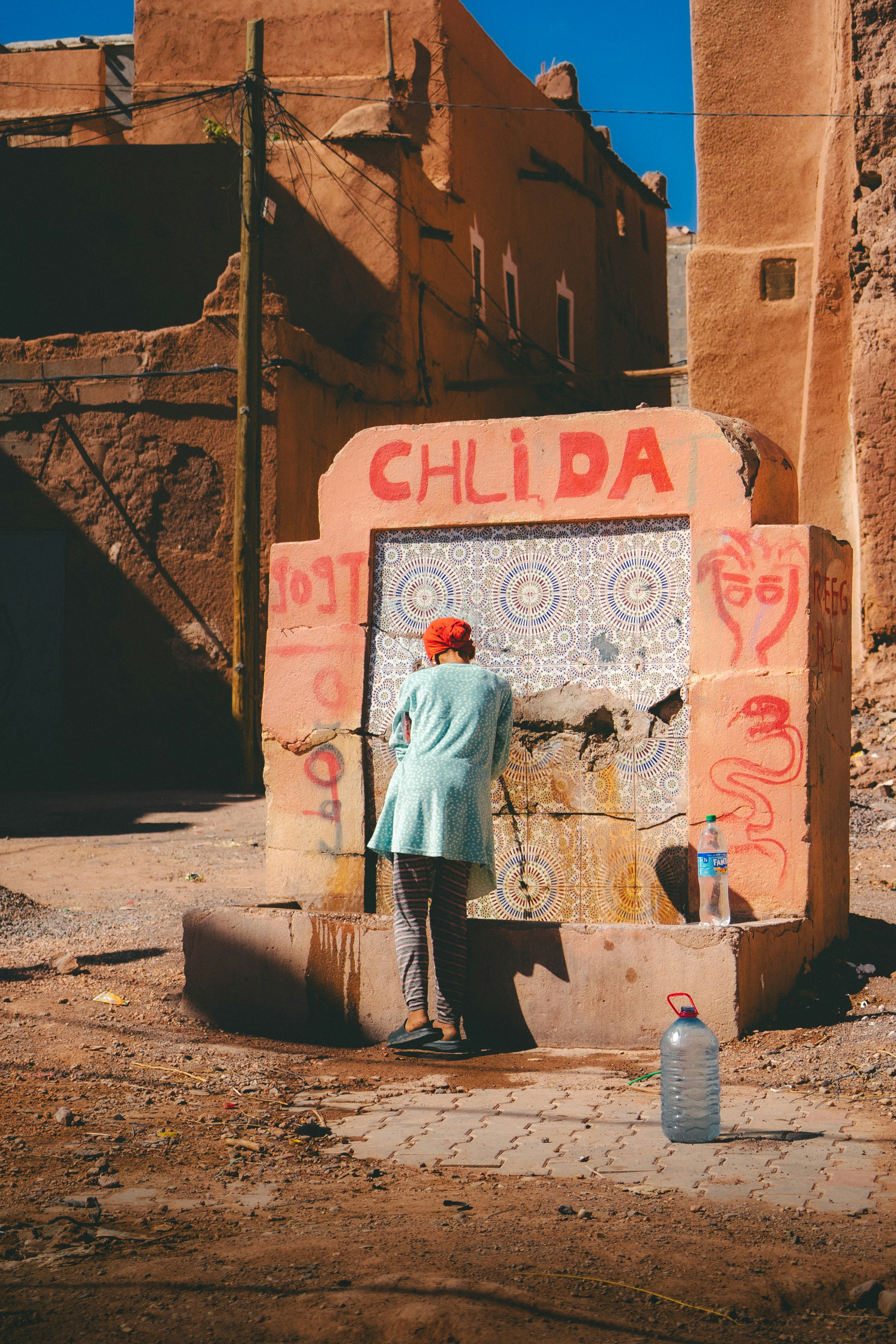 Woman filling water bottles at a public fountain.