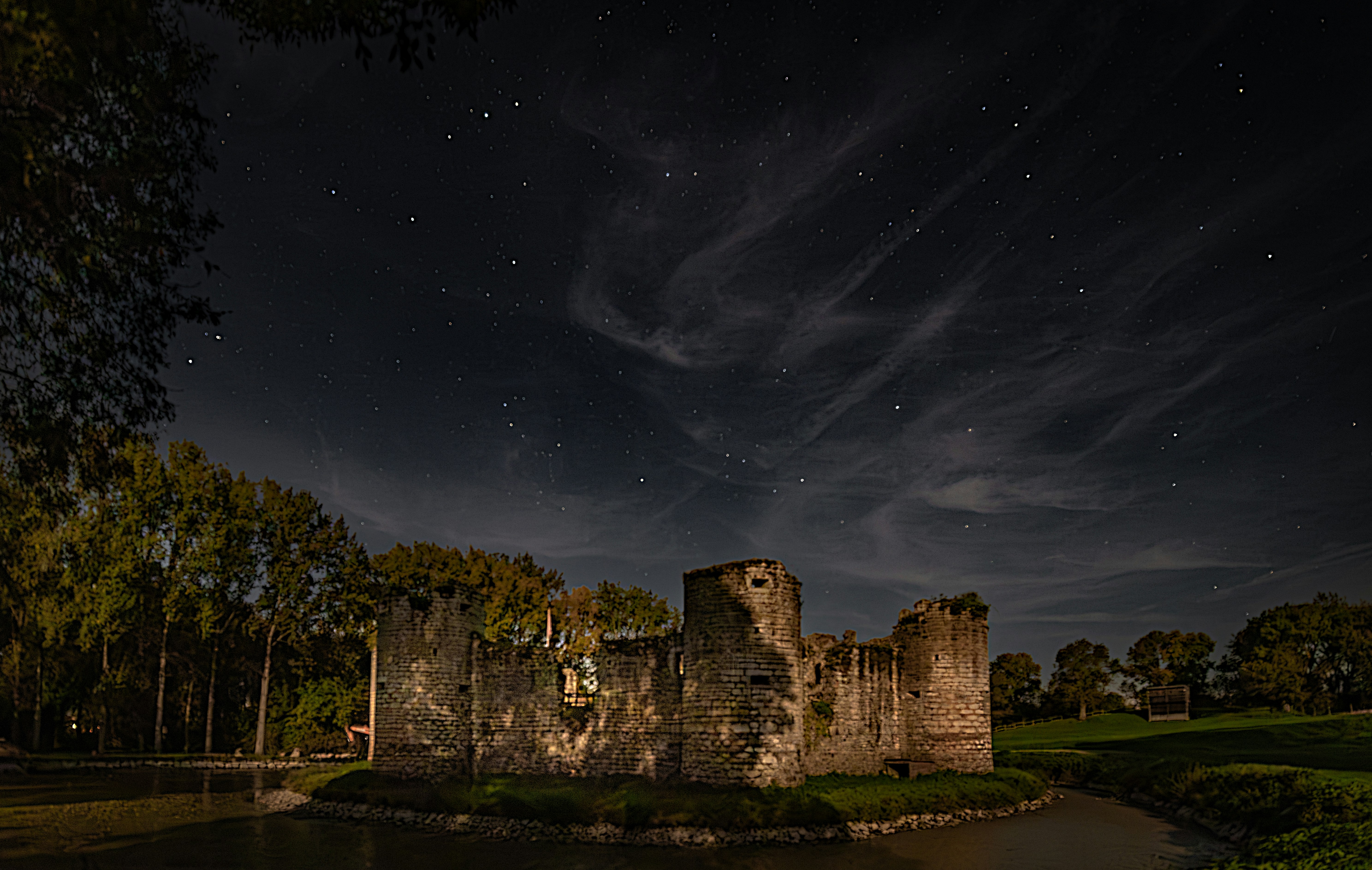 Ruined castle under starry night sky with wispy clouds