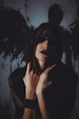 Woman with dark makeup and shadow wings behind her.