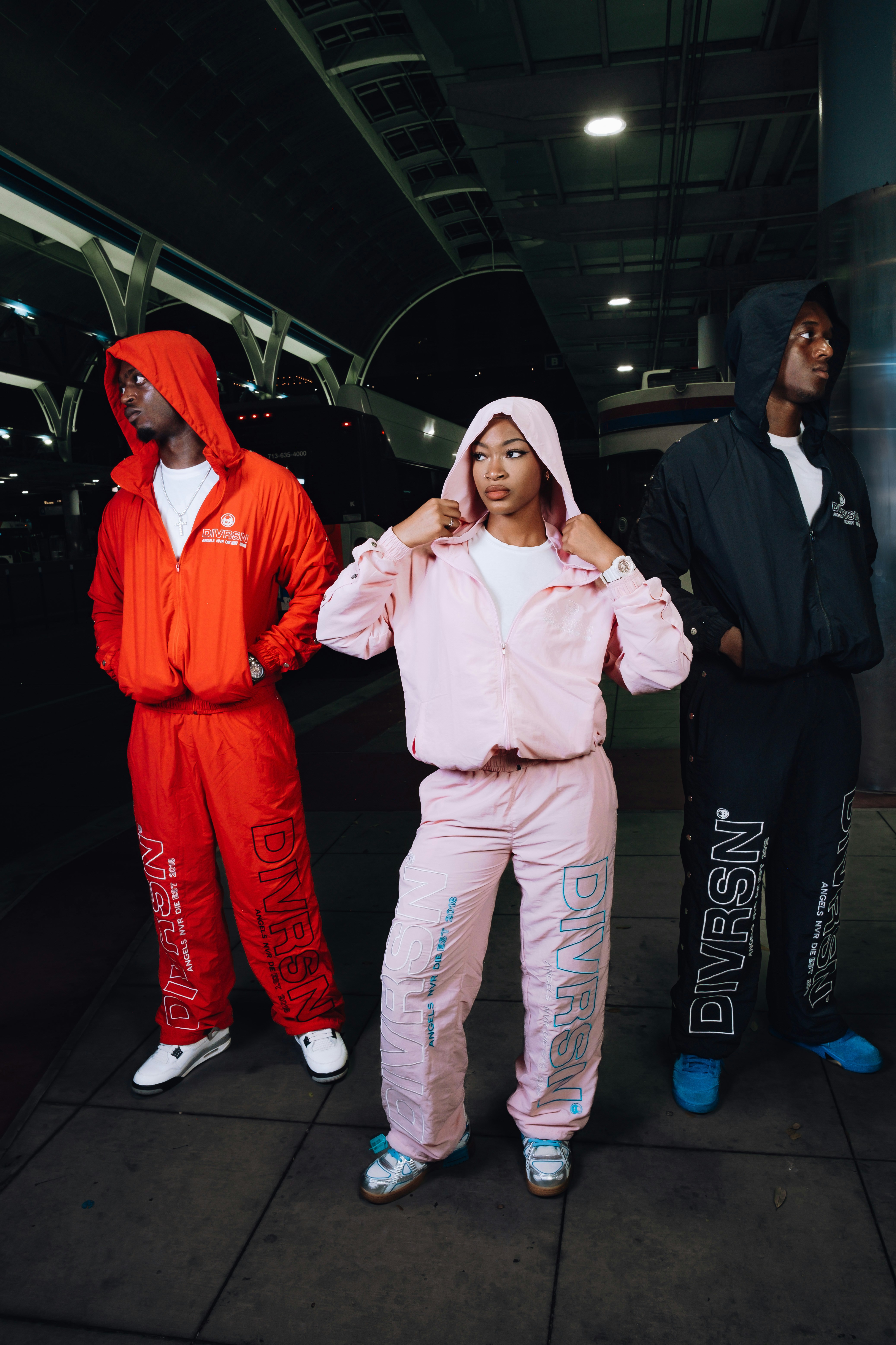 Three people in matching tracksuits outdoors at night.