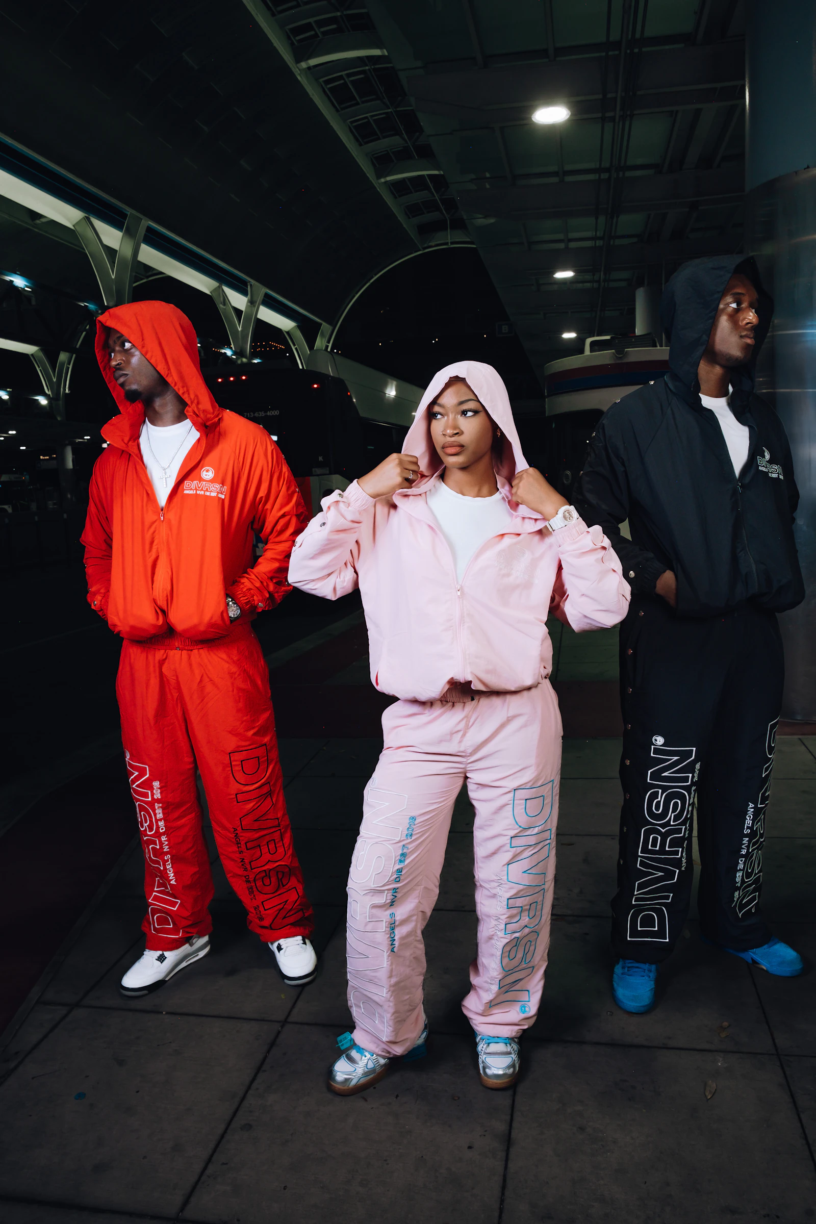 Three people wearing coordinated matching tracksuits outdoors