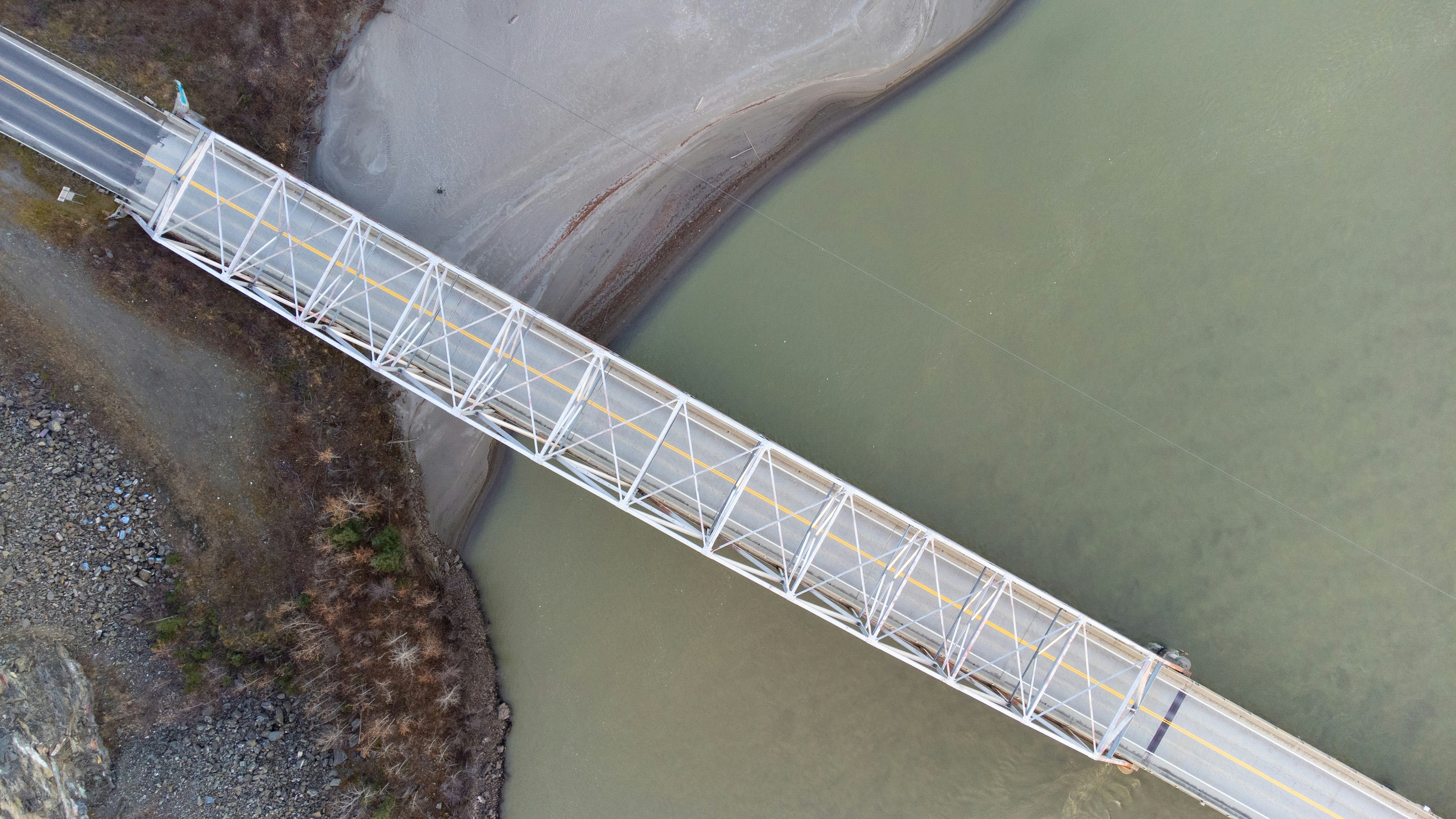 White truss bridge over muddy water