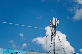 Cell tower against a bright blue sky with clouds