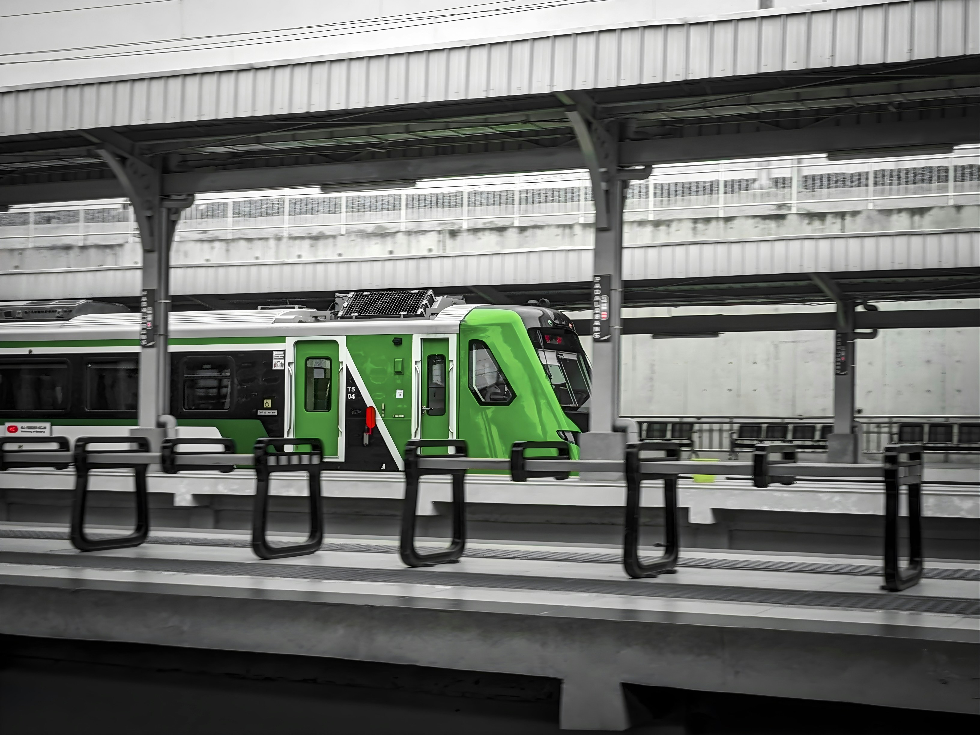 Green and white train at a station platform.