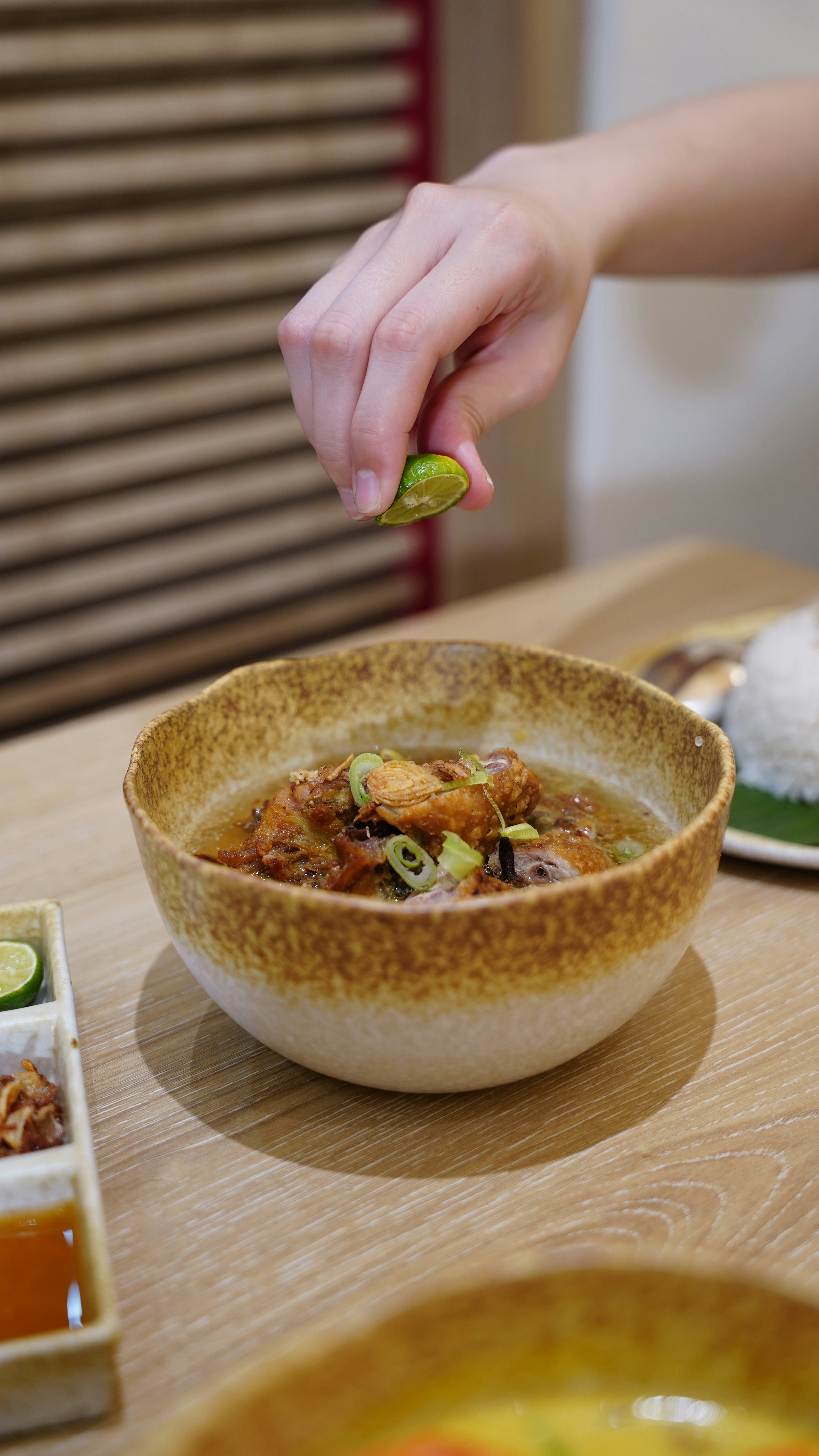 Hand squeezing lime over a bowl of stew
