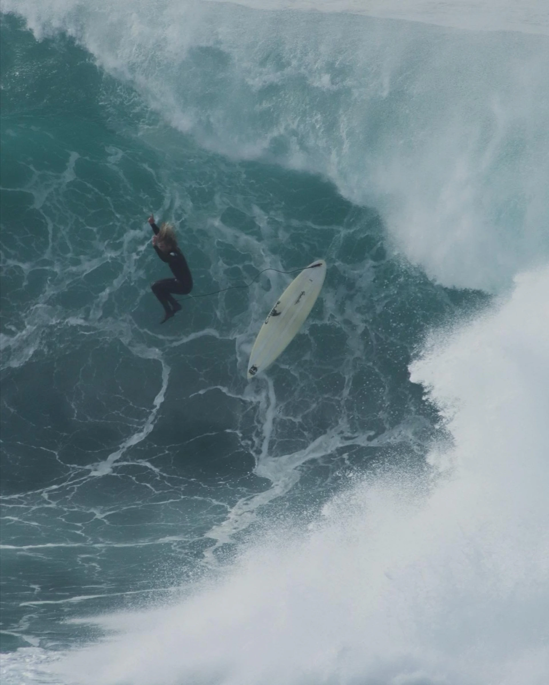 Surfer falling from surfboard on large wave