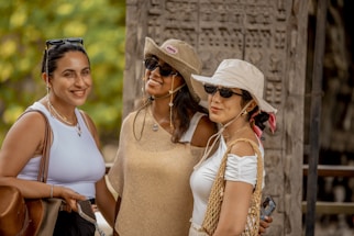 Three women wearing hats and sunglasses outdoors