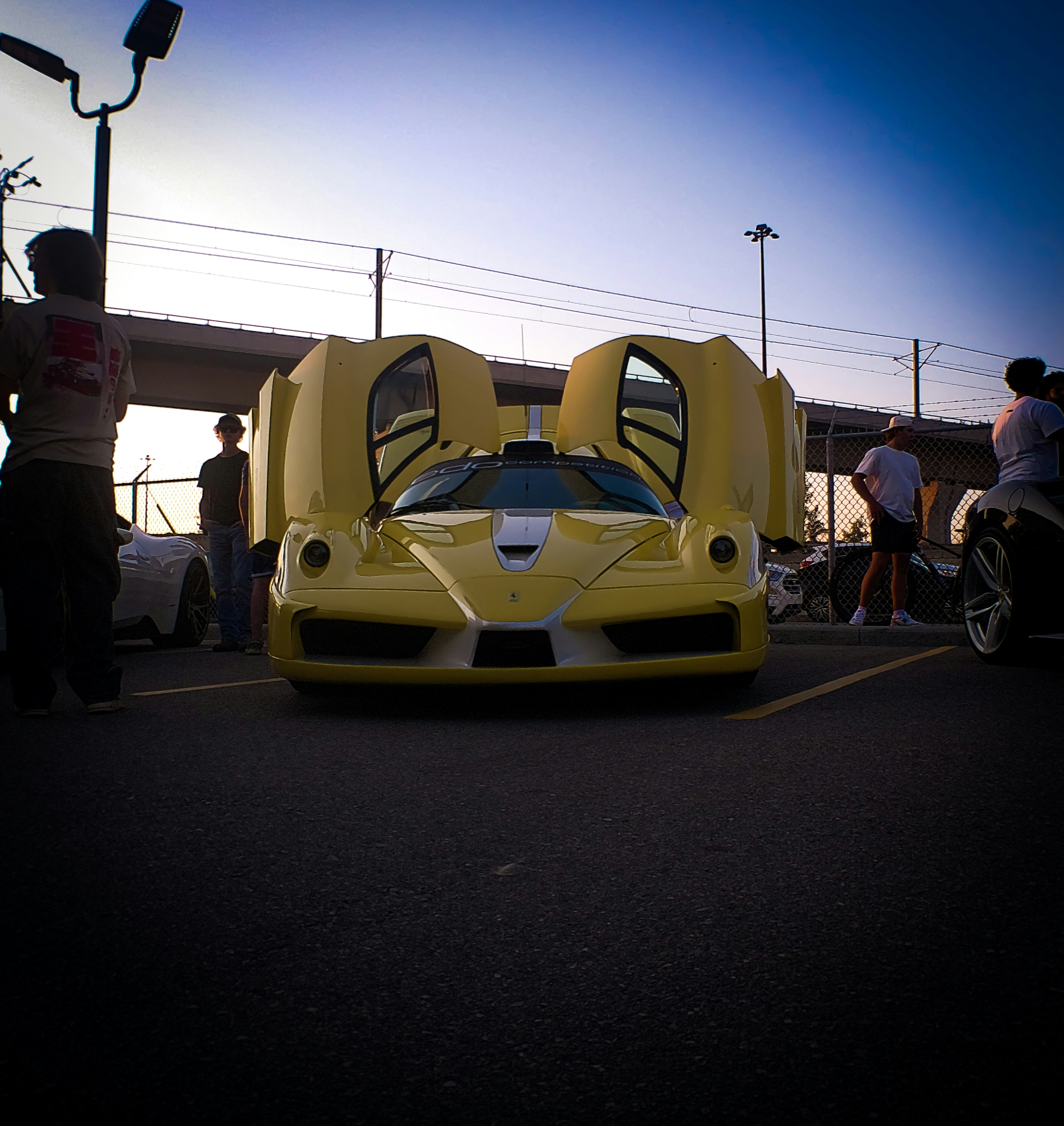 Yellow sports car with doors open at dusk