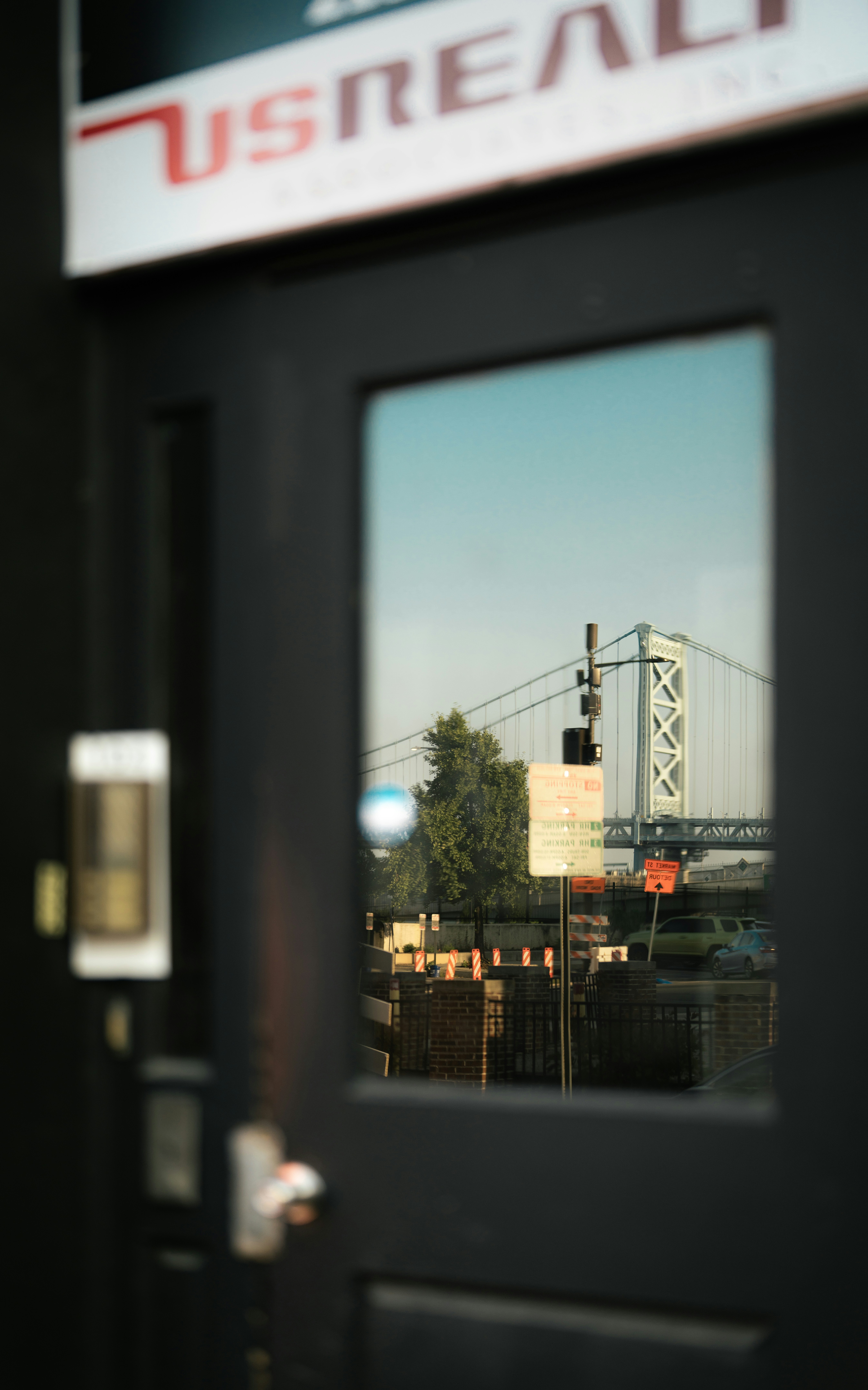 A bridge reflected in a glass door with signage.