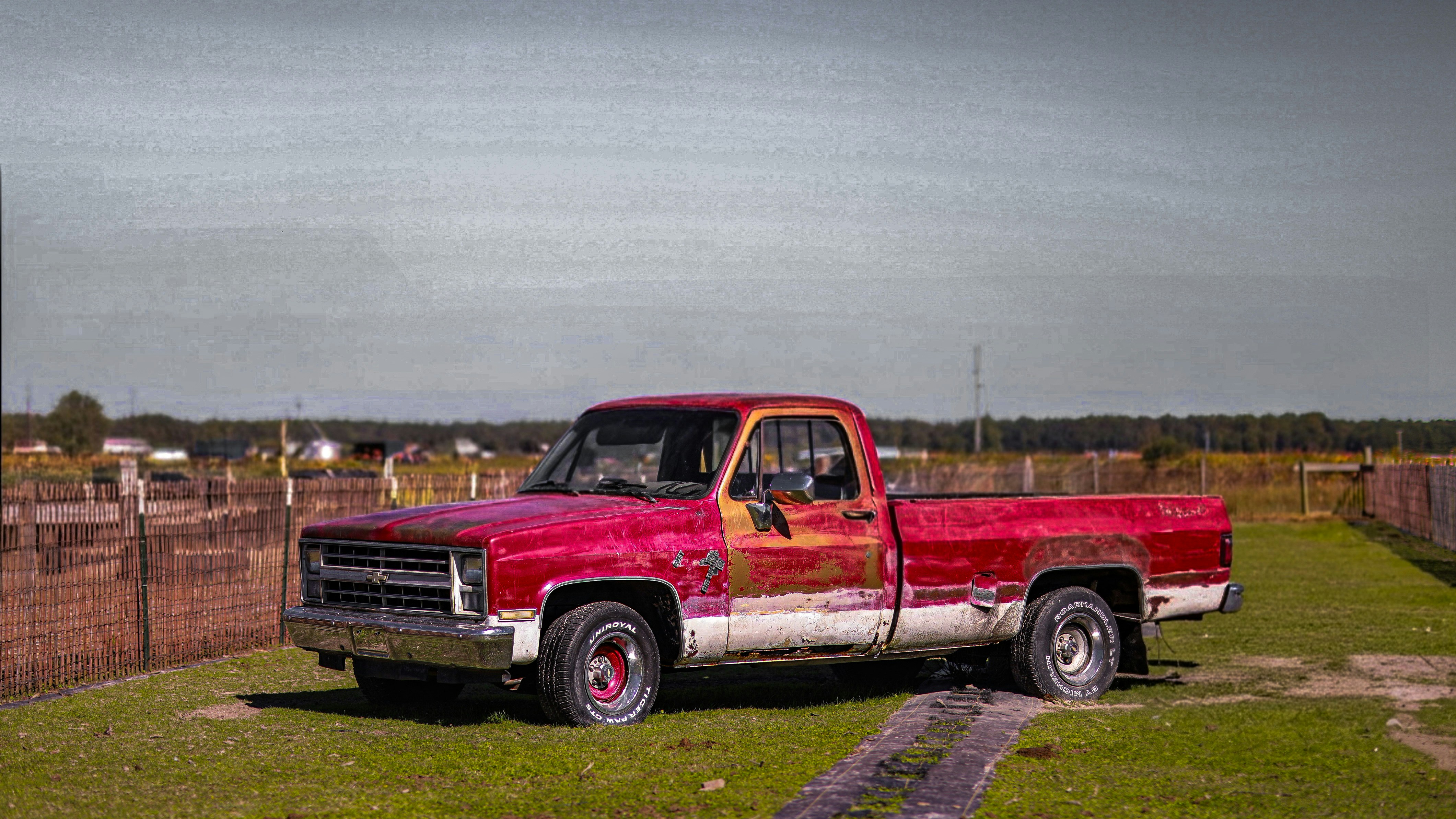 A weathered red and white pickup truck parked outdoors.