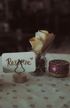 A reserved table setting with a sign and small tin.