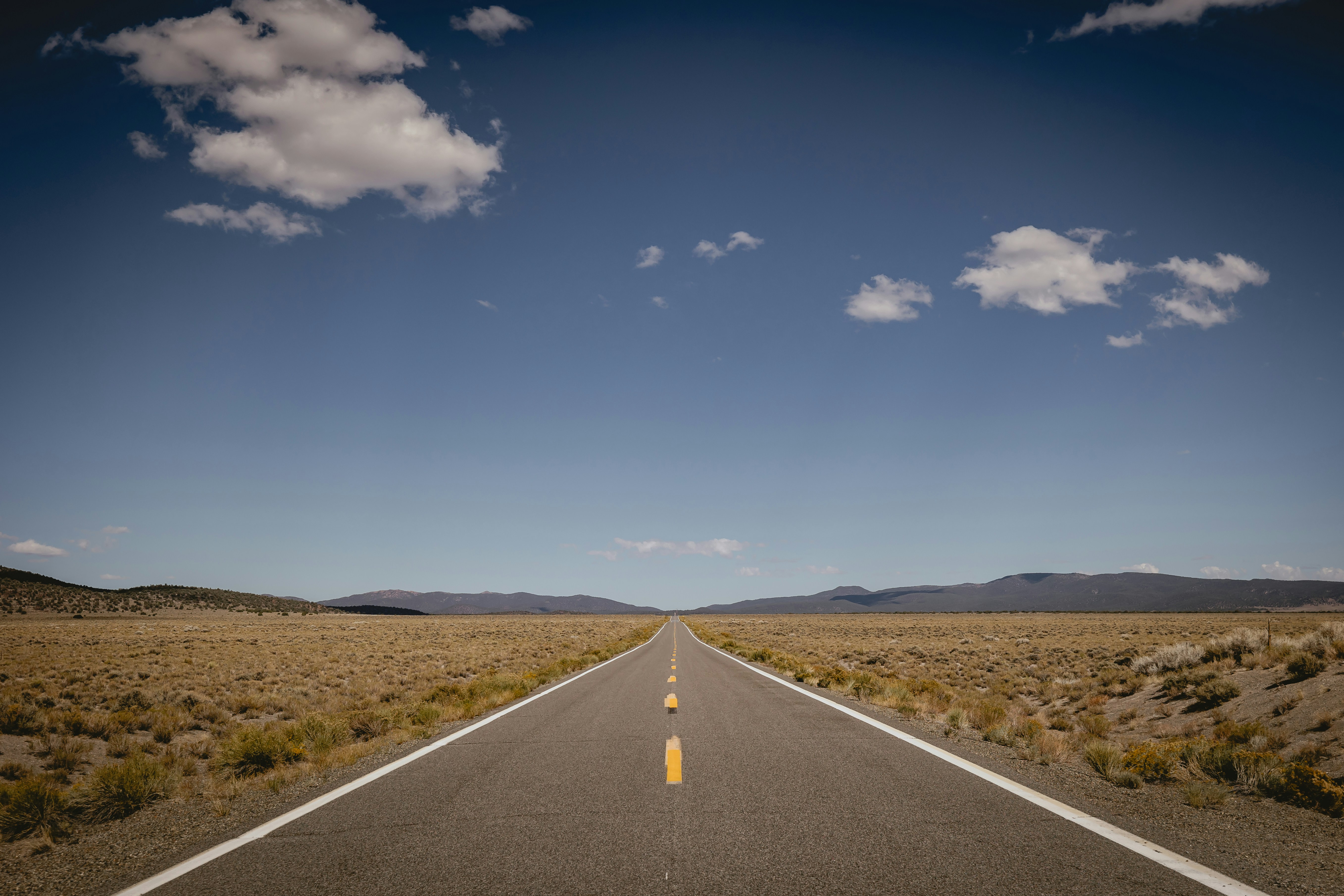 A long, straight road through a dry, open landscape. photo – Free Travel  Image on Unsplash, image size:3000x2000