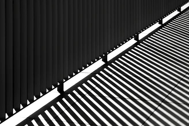 Shadows cast by a fence on a sunny day.