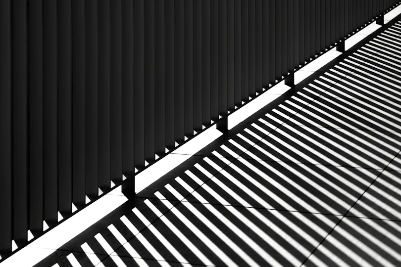 Shadows cast by a fence on a sunny day.