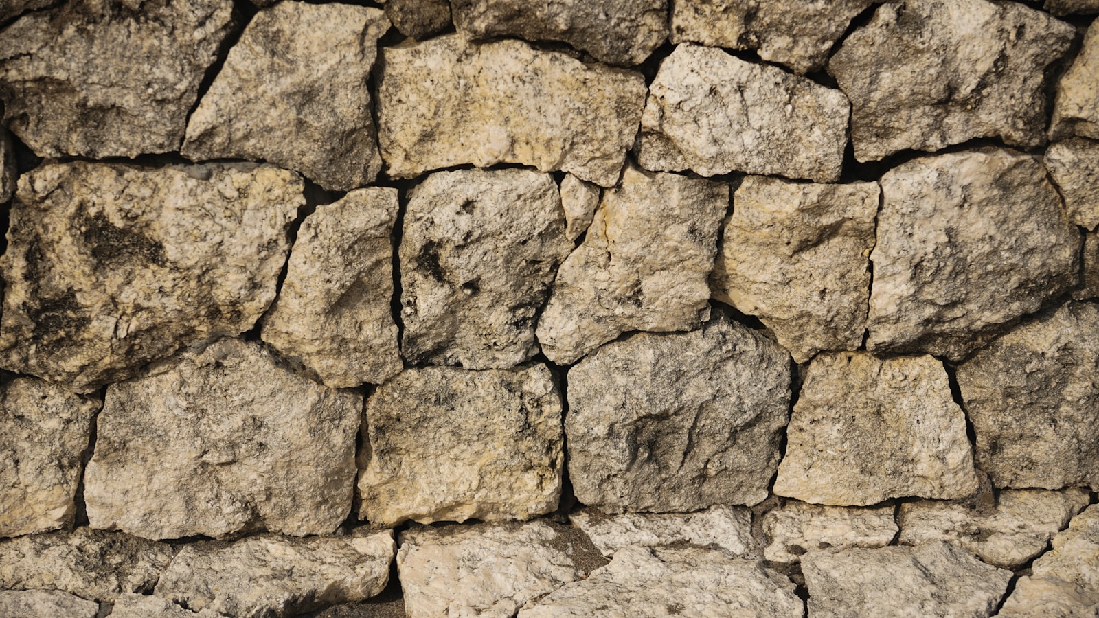 Irregular textured stone masonry wall — natural rock face detail, warm tones
