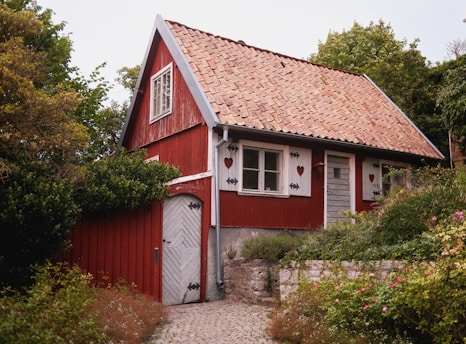 A charming red wooden house surrounded by lush greenery.