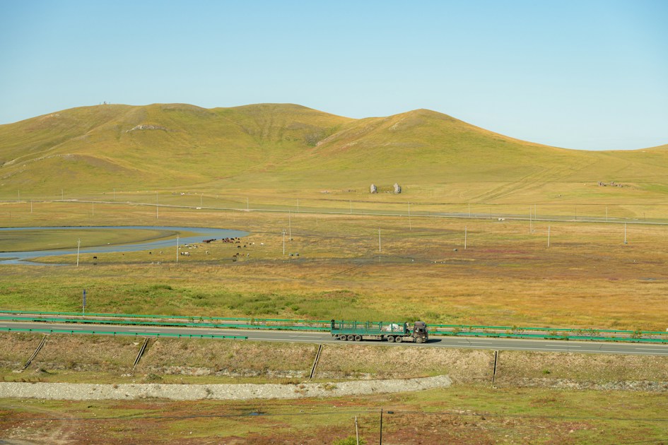 Truck driving on a road through rolling hills
