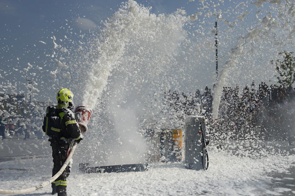 Firefighter sprays foam from a hose at a training exercise.