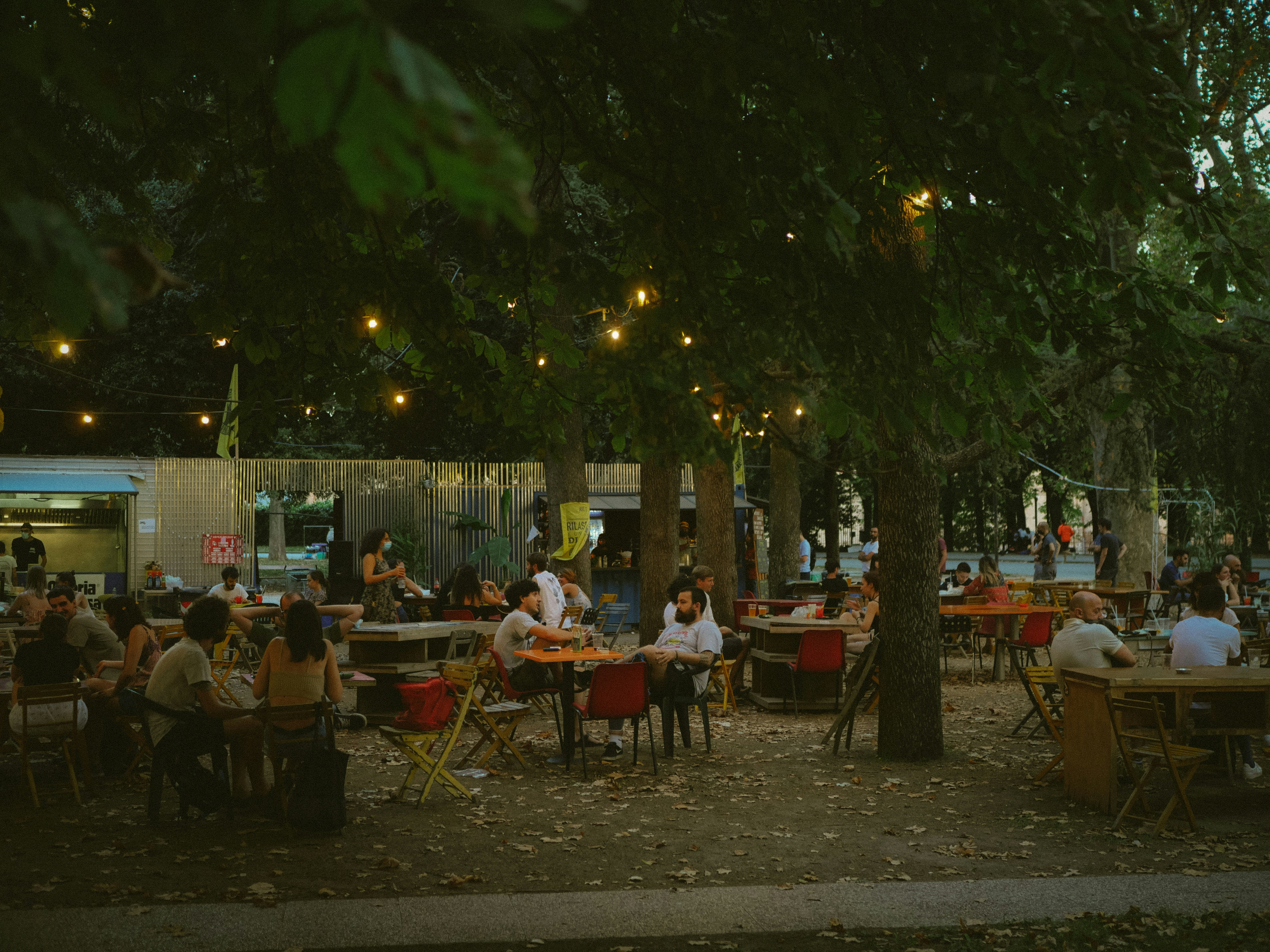 People dining outdoors under string lights in trees