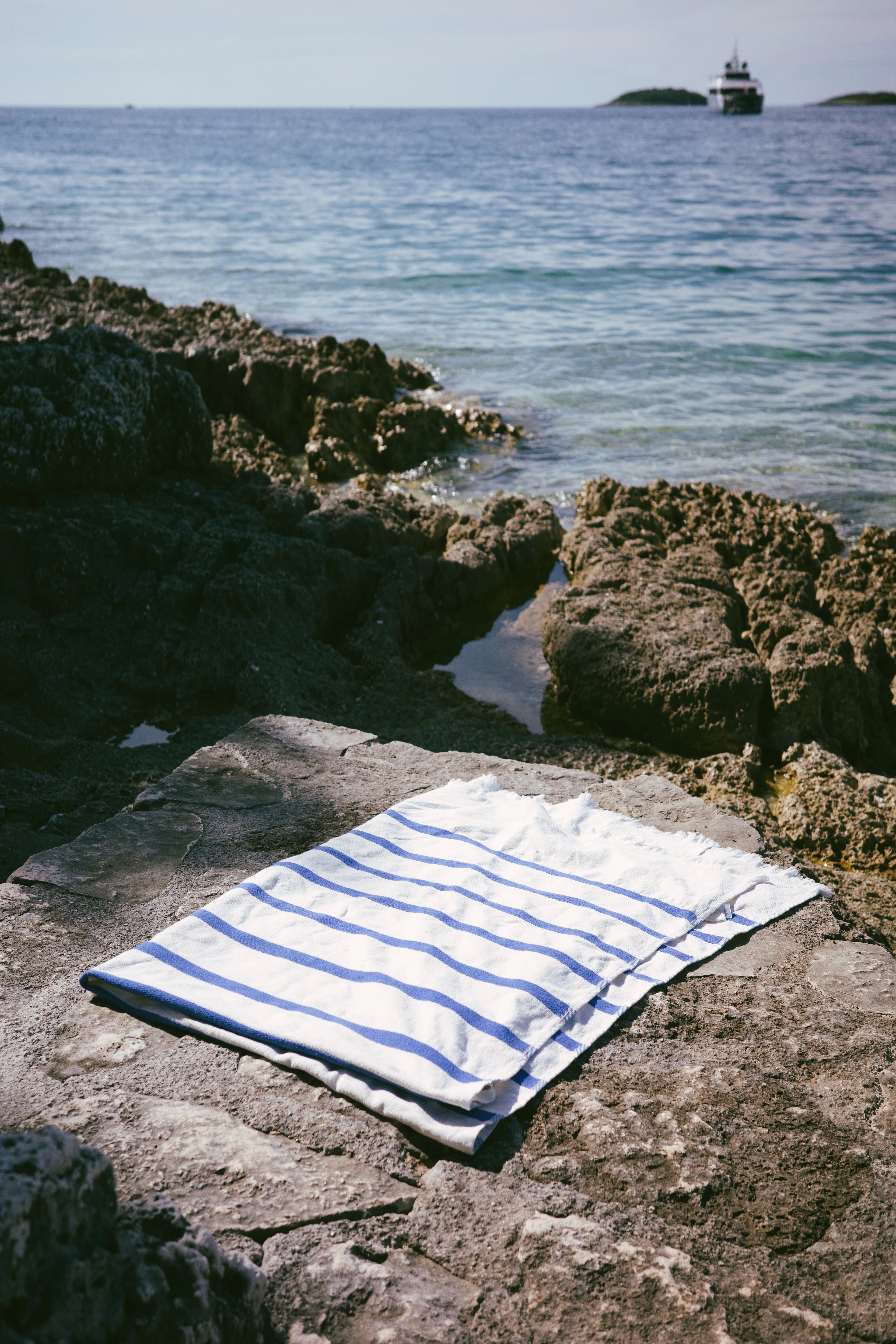 White towel with indigo stripes on coastal rocks
