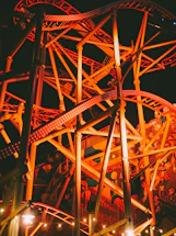 Roller coaster illuminated with orange lights at night