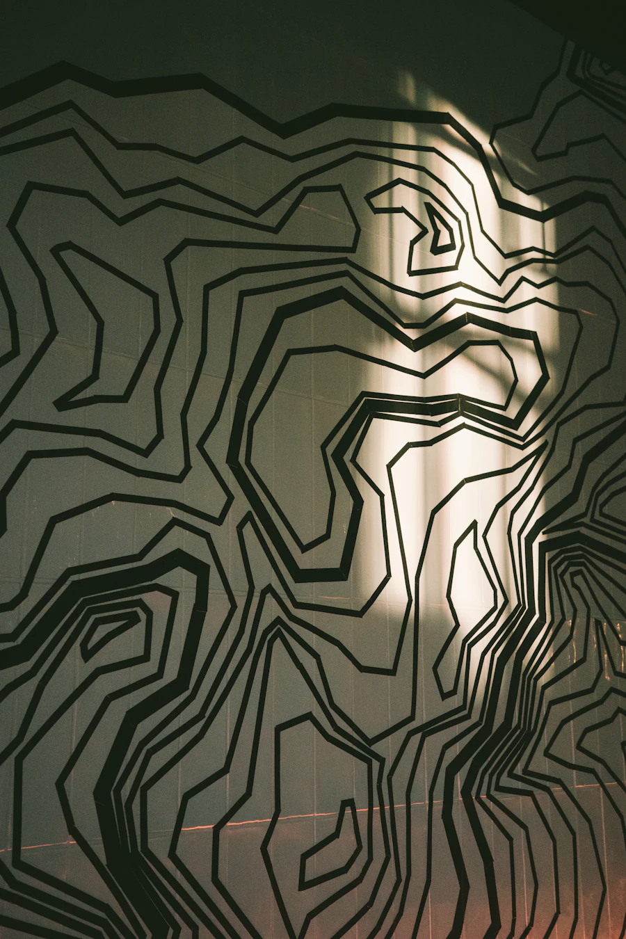 Fine contour lines traced across a wall in raking daylight