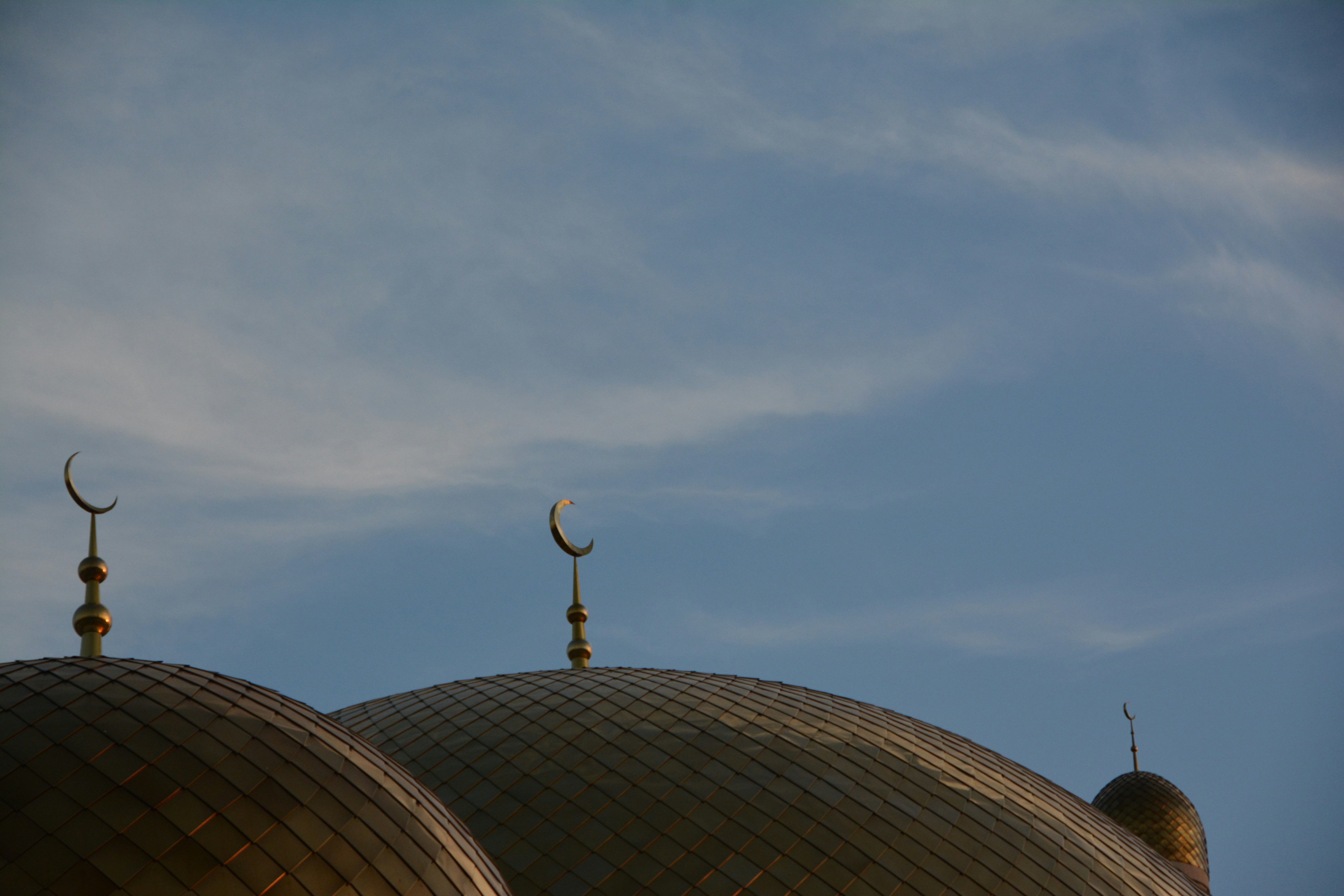 Golden mosque domes with crescent moons against sky