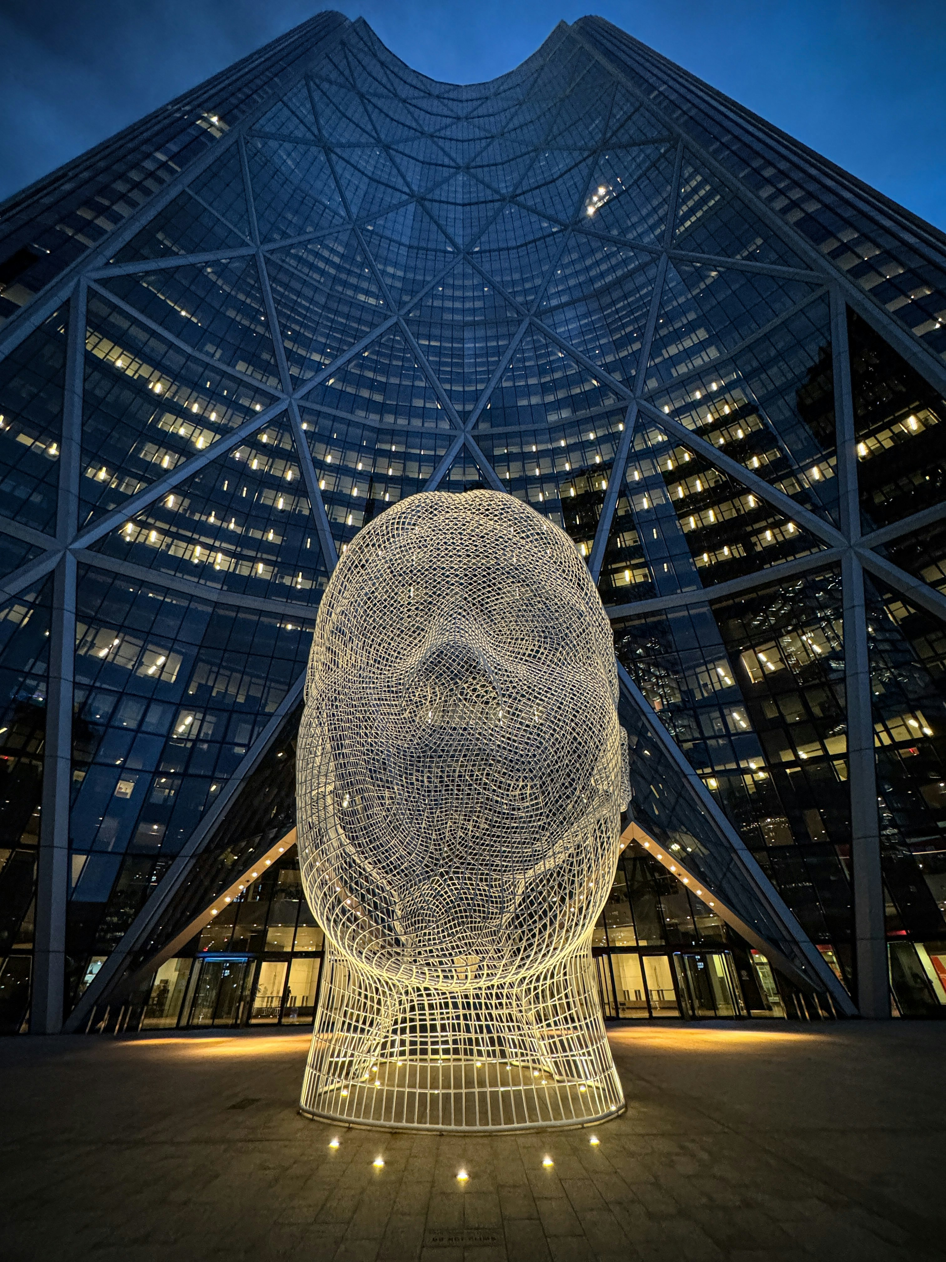 Wireframe head sculpture in front of modern building
