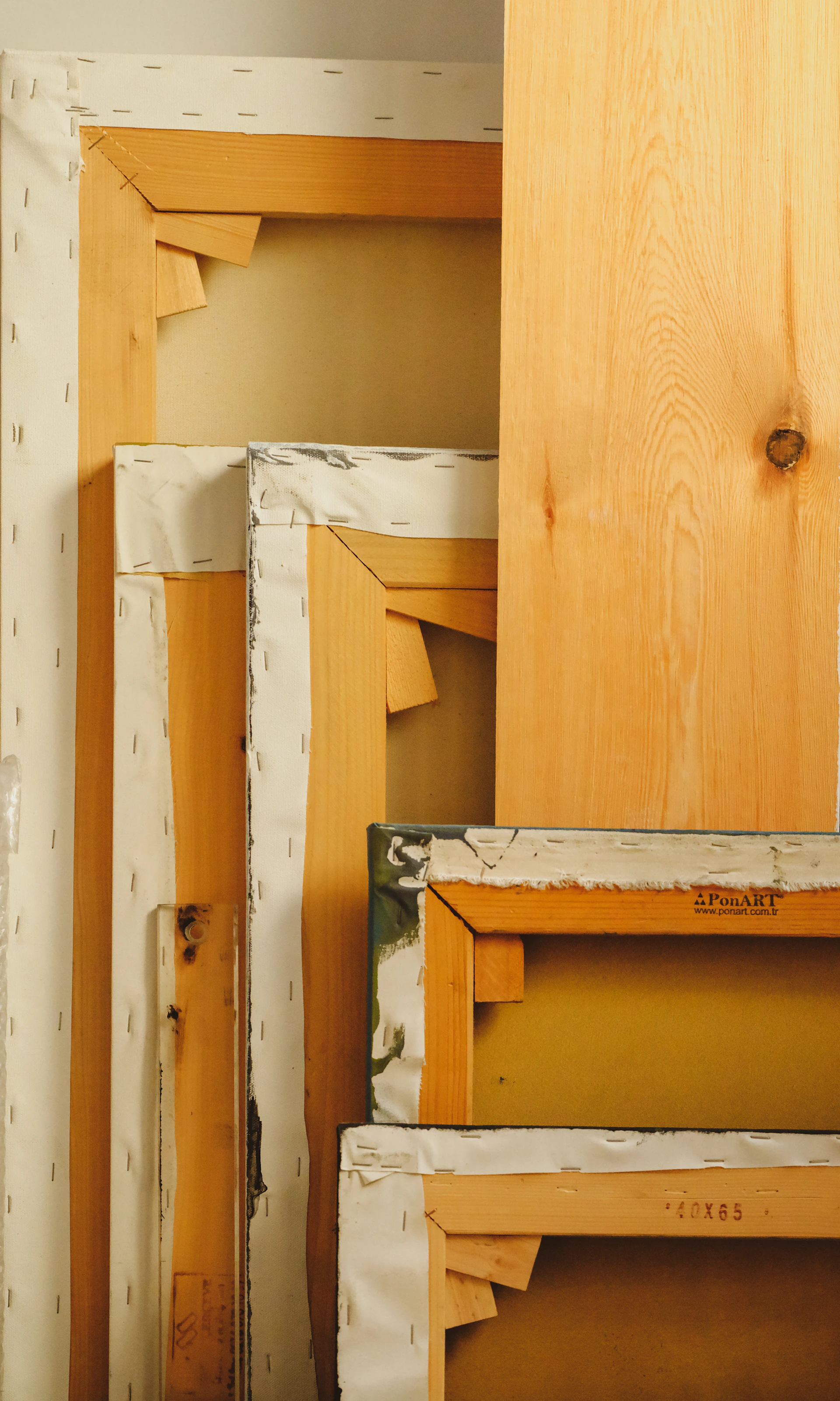 Stacked canvases and wooden boards in studio.